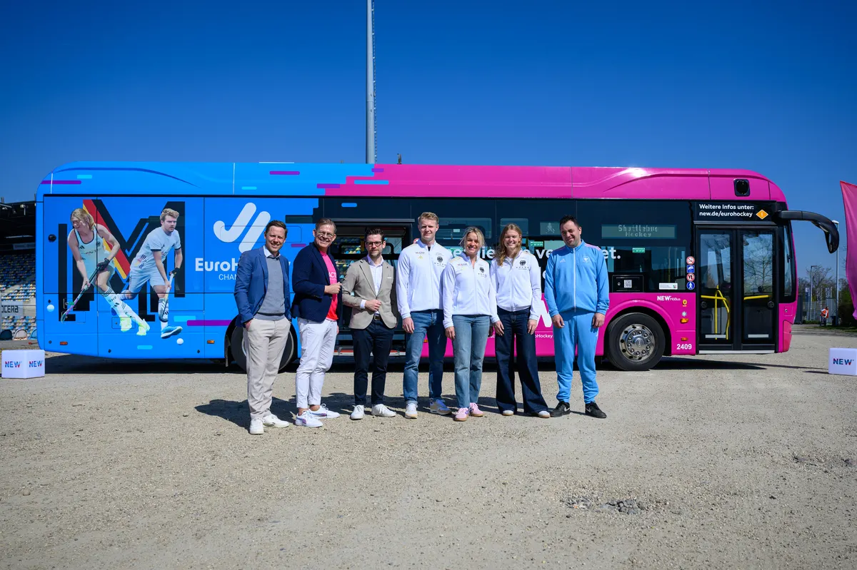NEW-Hockeybus Vor dem blau-pinken Hockey-Bus der NEW von links nach rechts: Julien Keibel, Kaufmännischer Vorstand des DHB, Frank Kindervatter, Vorstand der NEW, Felix Heinrichs, OB der Stadt Mönchengladbach, Tom Grambusch, Julia Sonntag, Lilly Stoffelsma, Dennis Steins