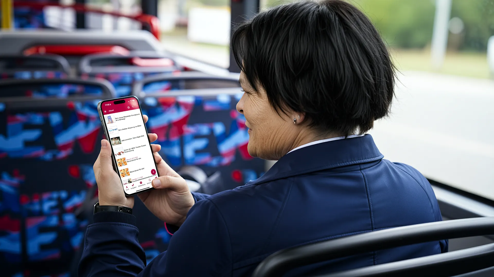 Eine Frau sitz im Bus und schaut auf ihr Handy. Dieses Bild wurde mit Hilfe von KI erstellt Eine Frau mit schwarzem Bob-Haarschnitt in dunkelblauer Jacke betrachtet eine Fahrplan-App auf ihrem Smartphone an einem Bus. Im Hintergrund sind Sitzrehen mit blau-rotem Muster zu sehen. Die Aufnahme zeigt die Nutzung digitaler Mobilitätsdienste im öffentlichen Nahverkehr. Dieses Bild wurde mit Hilfe von KI erstellt