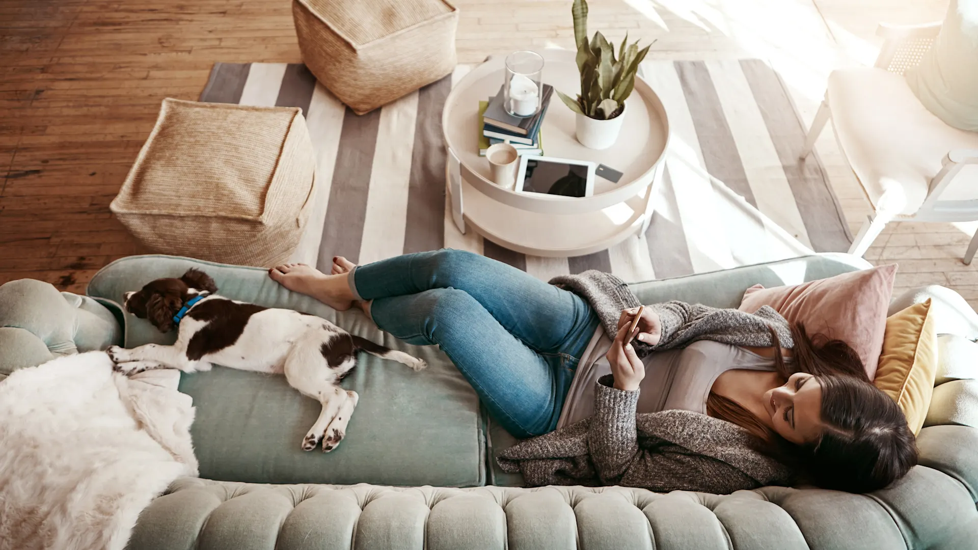 Frau schaut über ihr Smartphone nach Stromtarifen Eine Frau liegt im Wohnzimmer auf dem Sofa und schaut nach Stromtarifen der NEW Energie.