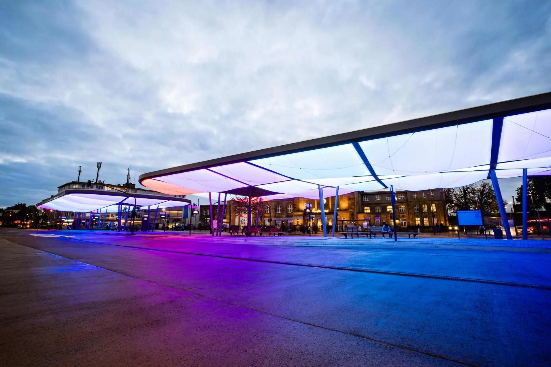 Busbahnhof Europaplatz in der Dämmerung Das Bild zeigt den Zentralen Omnibusbahnhof (ZOB) in Mönchengladbach in der Dämmerung. Die moderne Dachkonstruktion ist farbig beleuchtet und prägt das Stadtbild. Im Hintergrund befindet sich der Hauptbahnhof