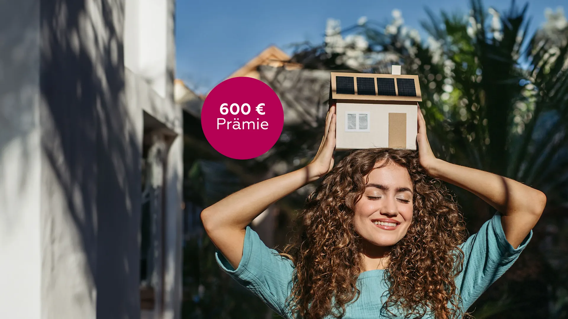 Frau mit-Hausmodell über dem Kopf Frau freut sich über die hohe Prämie der NEW Energie für eine Photovoltaik-Anlage