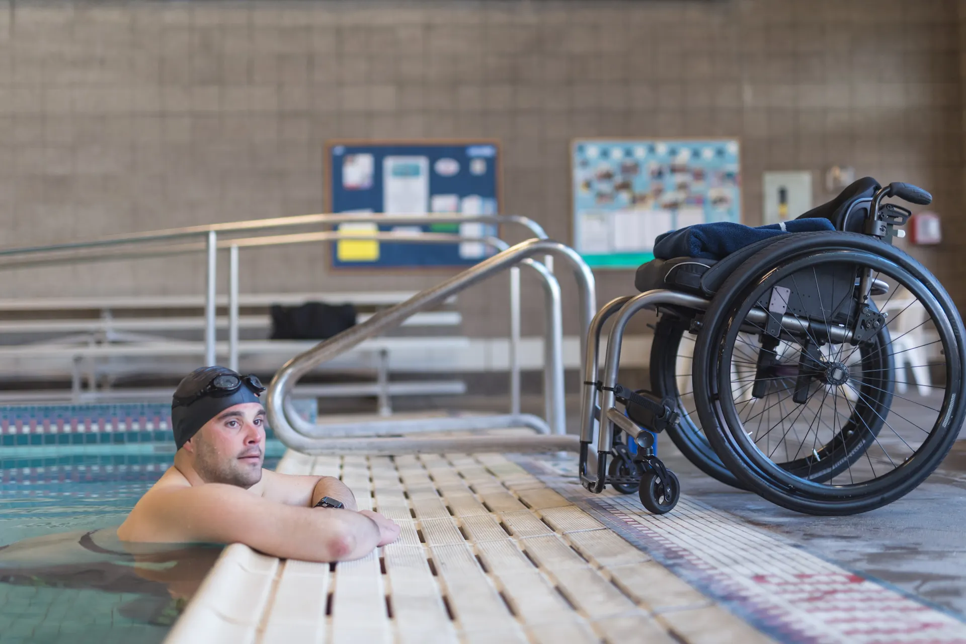 Schwimmen für alle: So sieht ein barrierefreies Schwimmbad aus (iStock / FatCamera) Ein Mann befindet sich in einem Schwimmbecken und lehnt mit den Armen am Beckenrand. Am Beckenrand steht ein Rollstuhl.