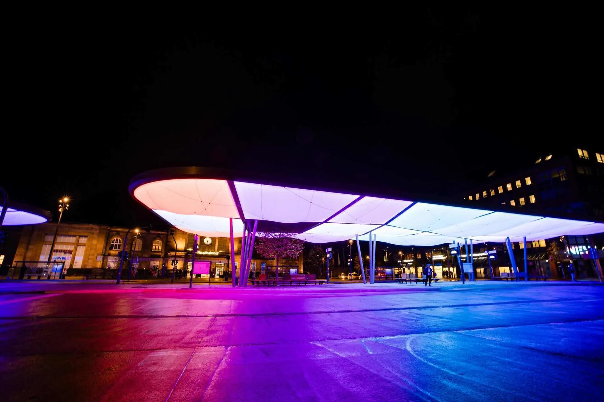 Busbahnhof Europaplatz farbig beleuchtet Das Bild zeigt den Zentralen Omnibusbahnhof (ZOB) in Mönchengladbach bei Nacht. Die moderne Dachkonstruktion ist farbig beleuchtet und prägt das Stadtbild. Im Hintergrund befindet sich der Hauptbahnhof