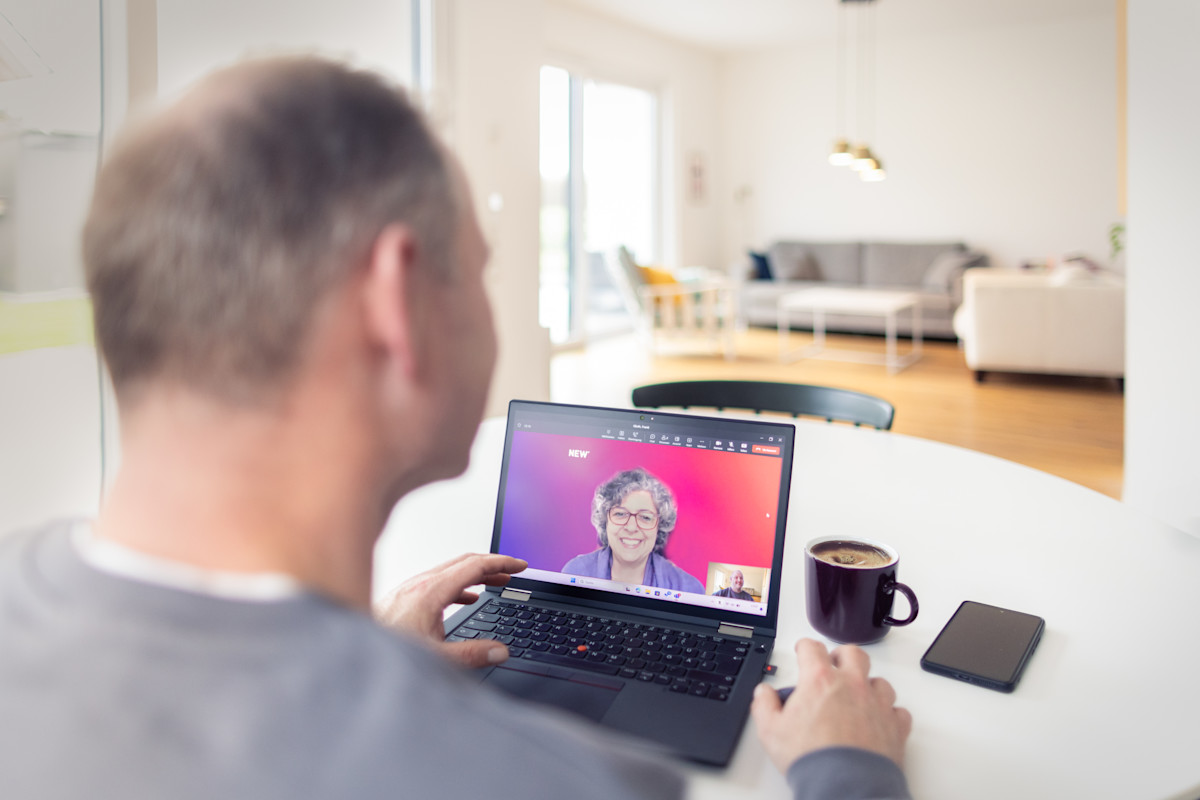 Ein Mann telefoniert über den Laptop per Video mit einer Kollegin.