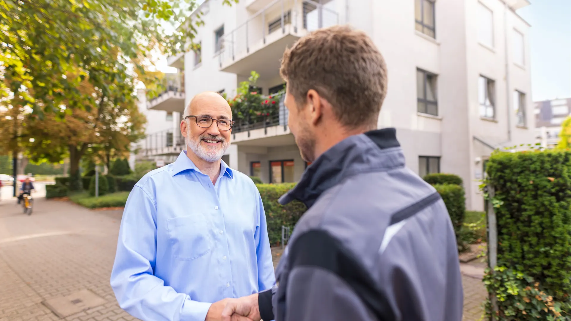 Kunde Installateur Mehrfamilienhaus Kunde und Installateur vor einem Mehrfamilienhaus