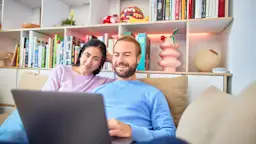 Ein Paar sitzt am Laptop und besucht die NEW Netz Website Ein Paar sitzt im Wohnzimmer an ihrem Laptop und besucht die NEW Netz Website
