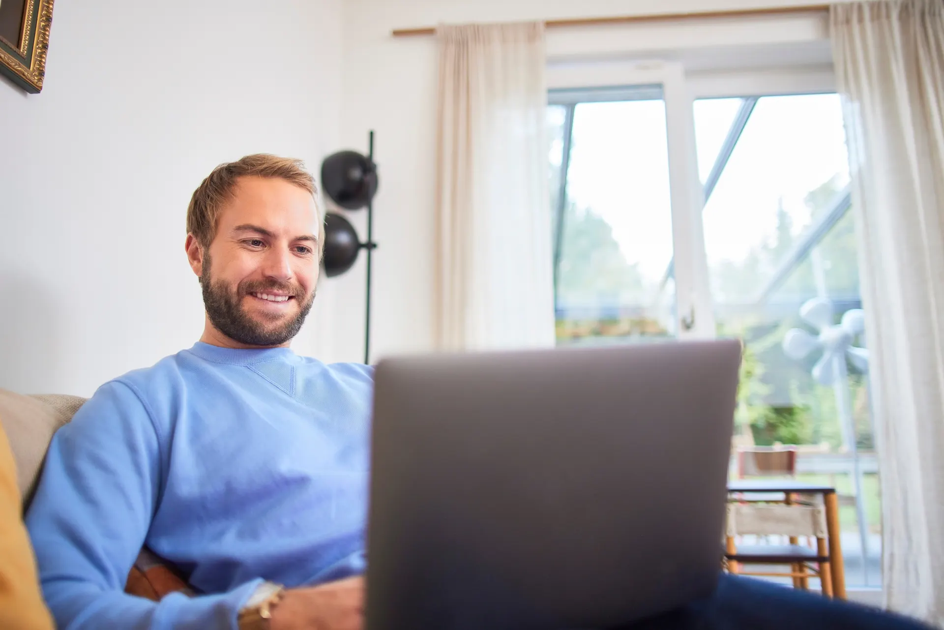 Ein Mann sitzt an seinem Laptop Ein Mann sitzt auf der Couch an seinem Laptop und ist auf der NEW Netz Website
