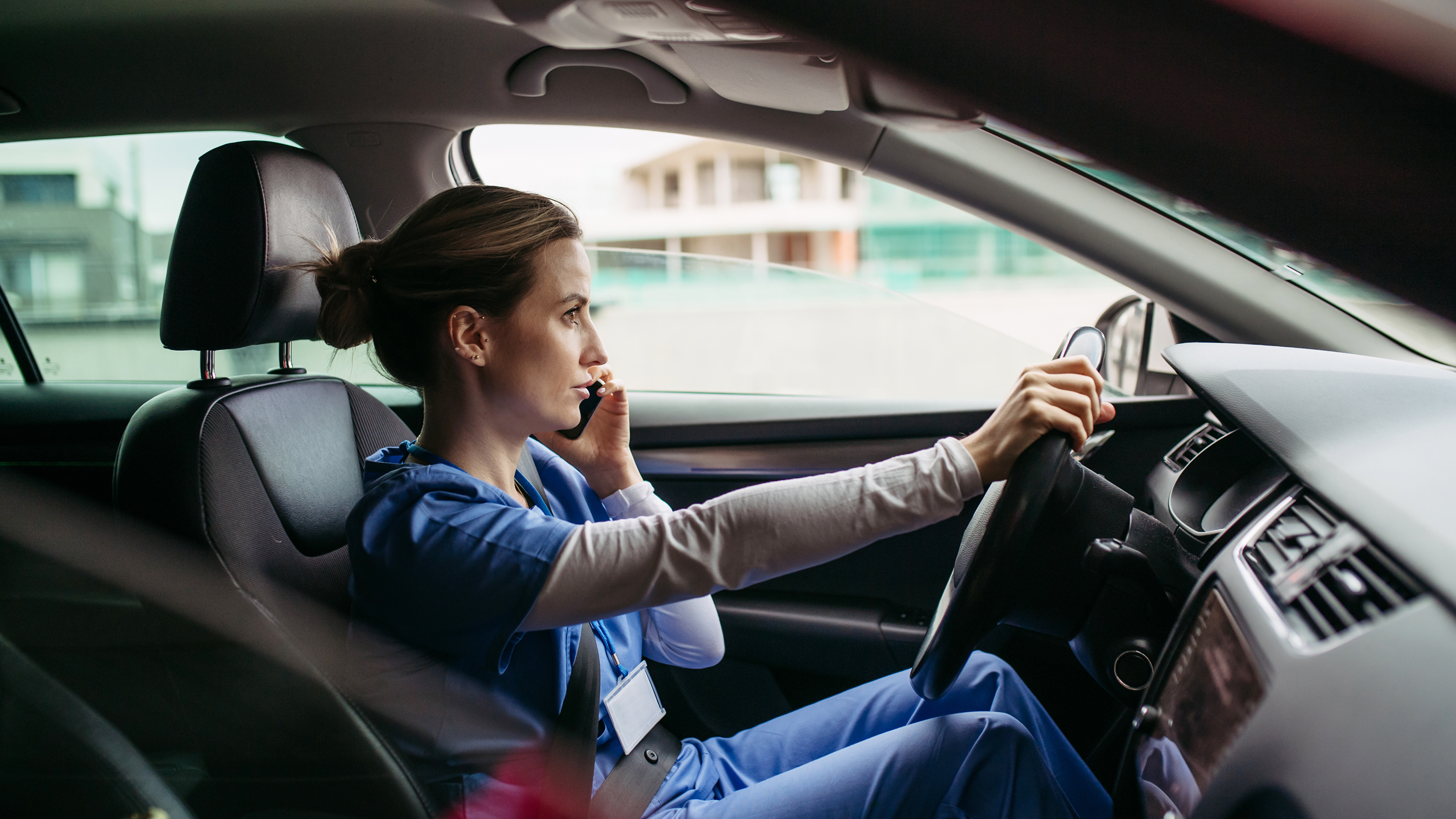 Frau mit Pflegedienstkleidung sitzt im Auto