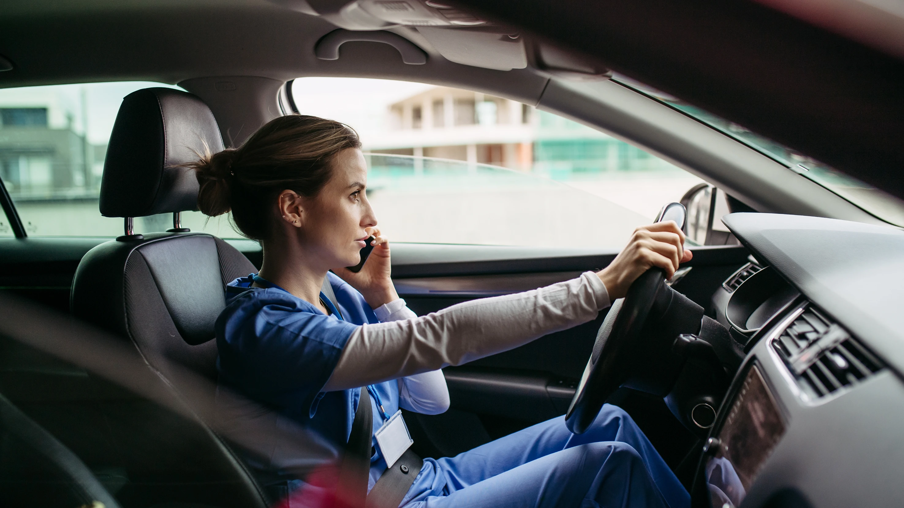 Frau mit Pflegedienstkleidung sitzt im Auto