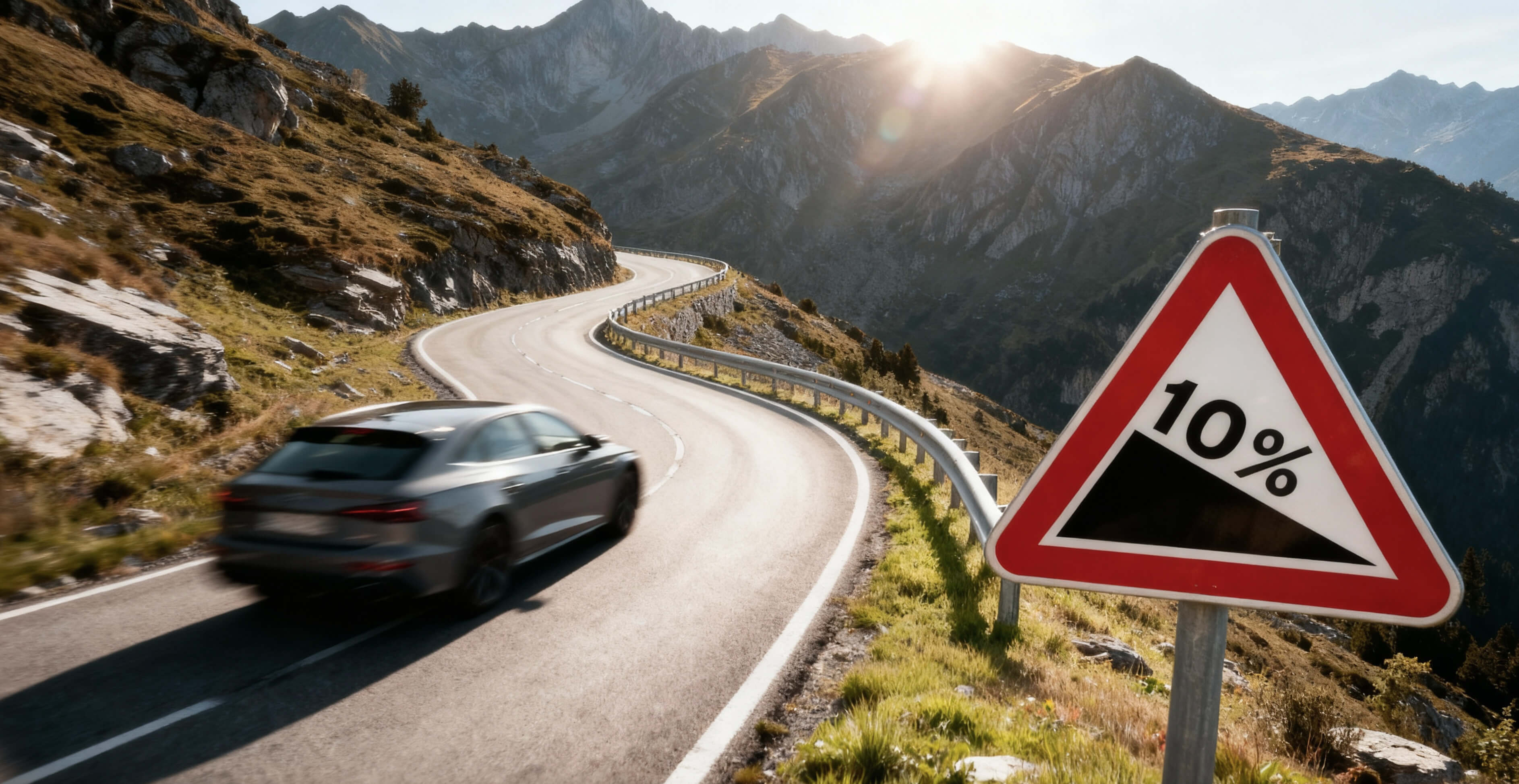 Auto fährt auf kurviger Bergstraße mit Warnschild 10% Steigung, Sonnenstrahlen über Alpengipfeln im Hintergrund