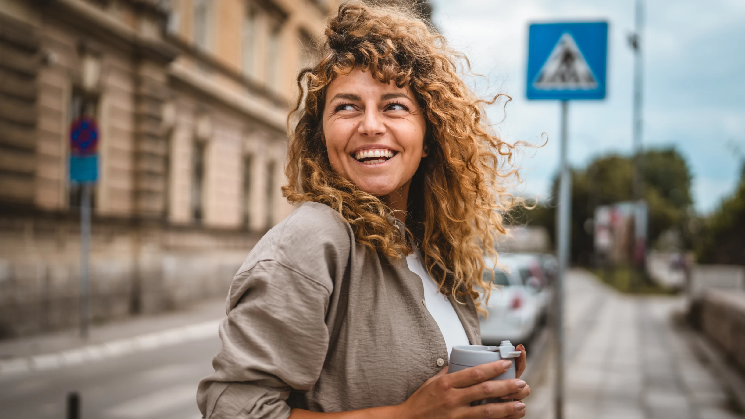 Frau auf der Strasse mit Becher in der Hand