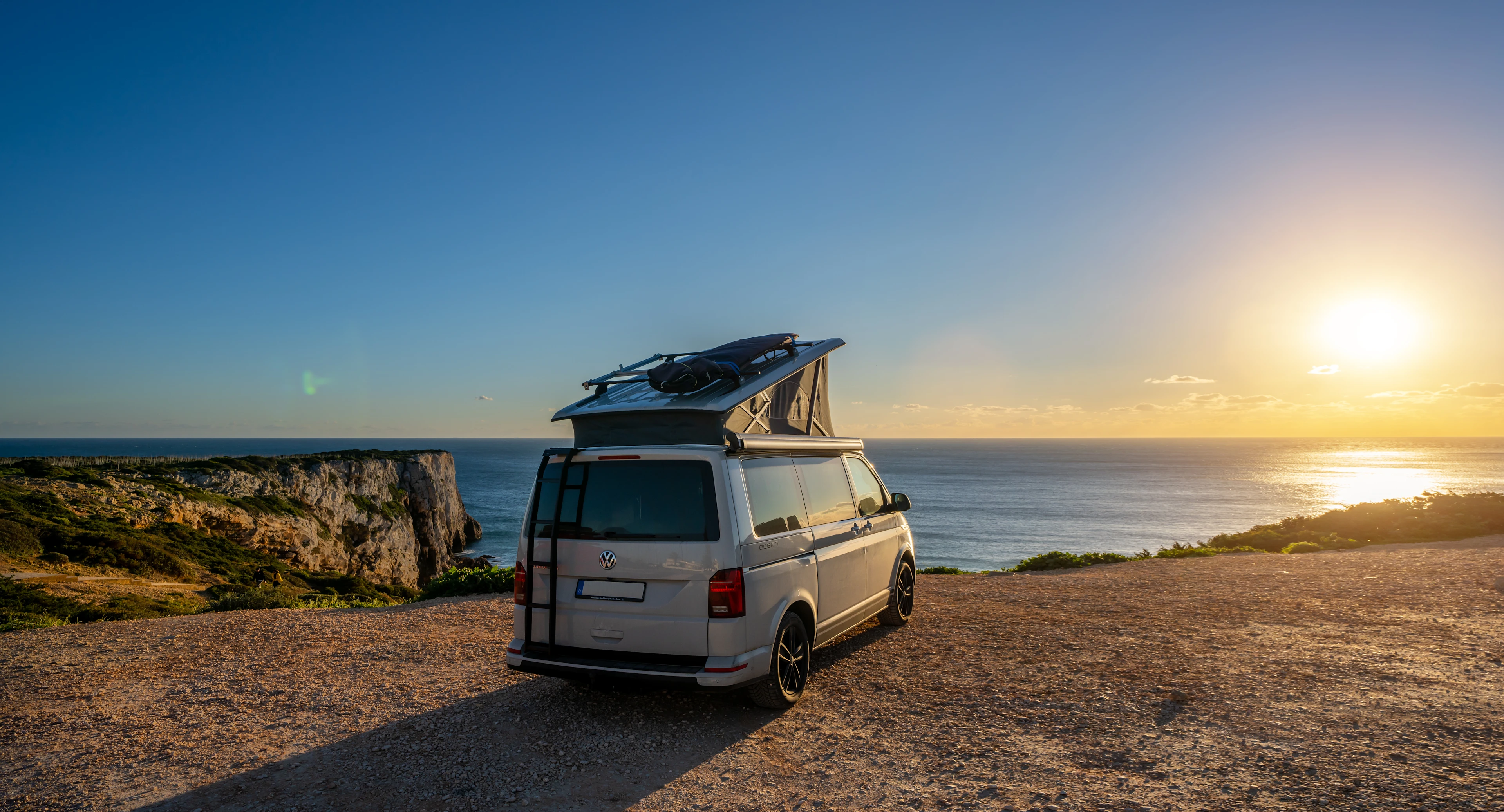 Campingbus steht an der Küste in der Abendsonne