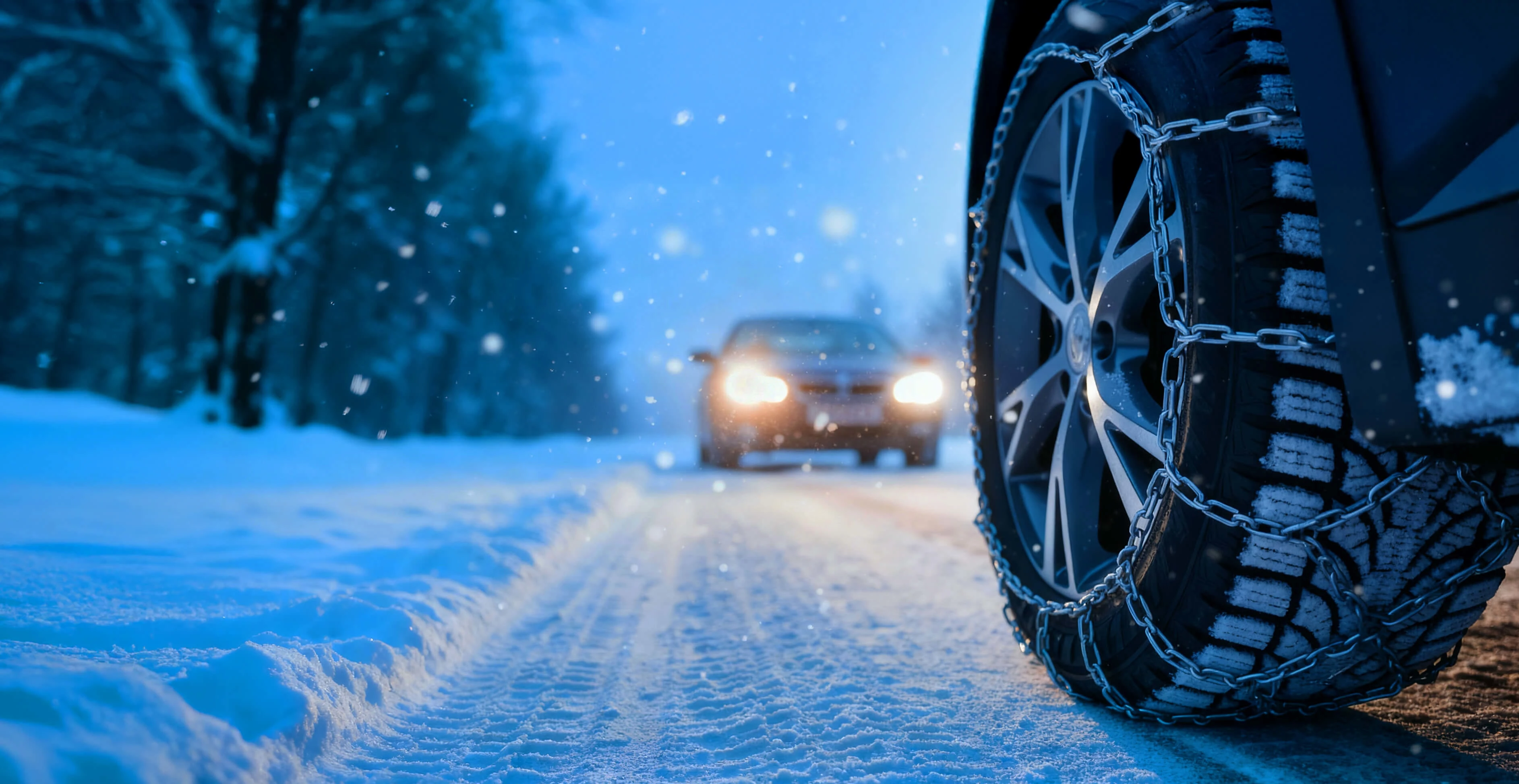 Autoreifen mit Schneeketten auf verschneiter Winterstraße
