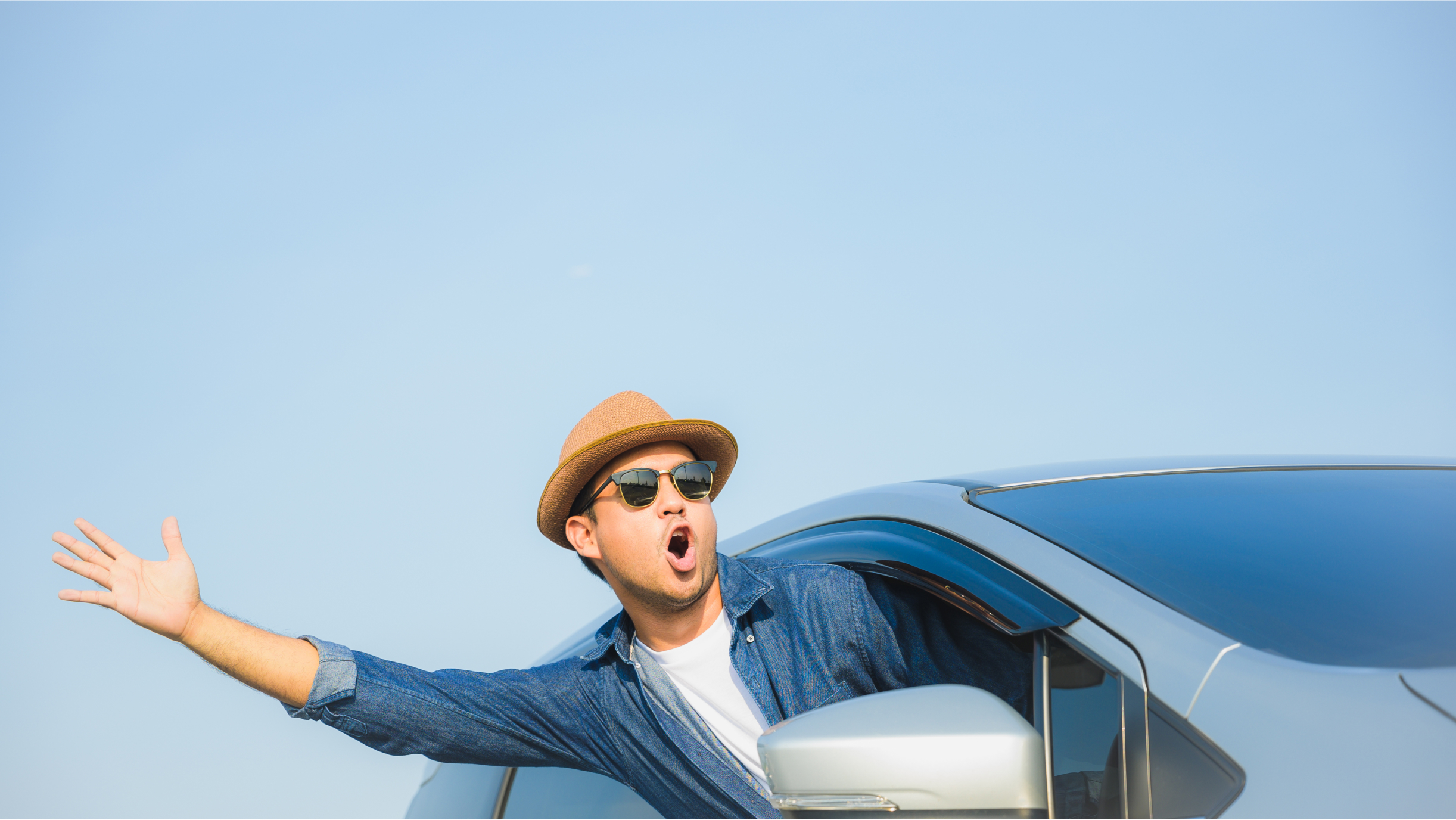 Mann winkt aus einem Auto 