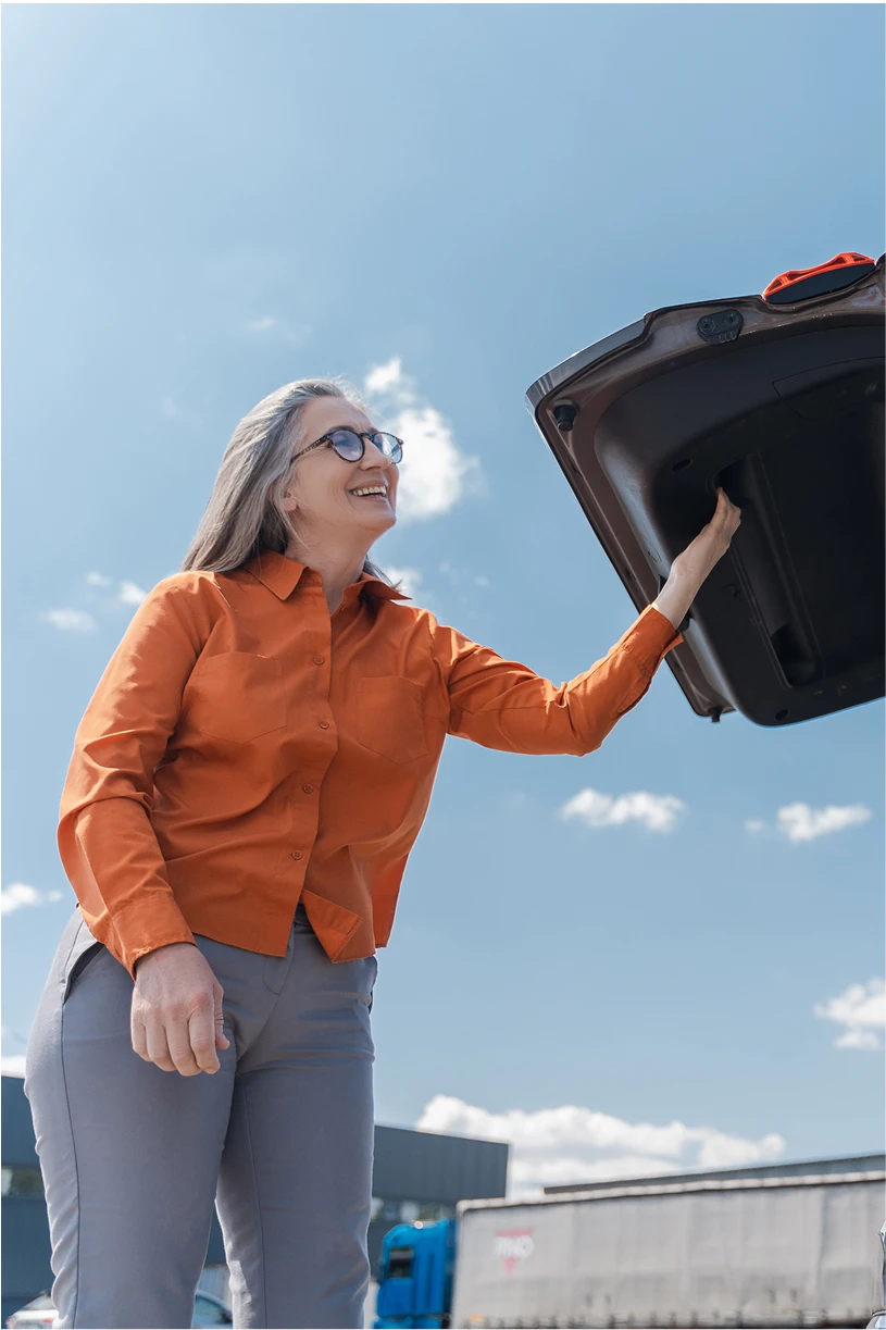 Frau steht am geöffneten Kofferaum eines SUVs