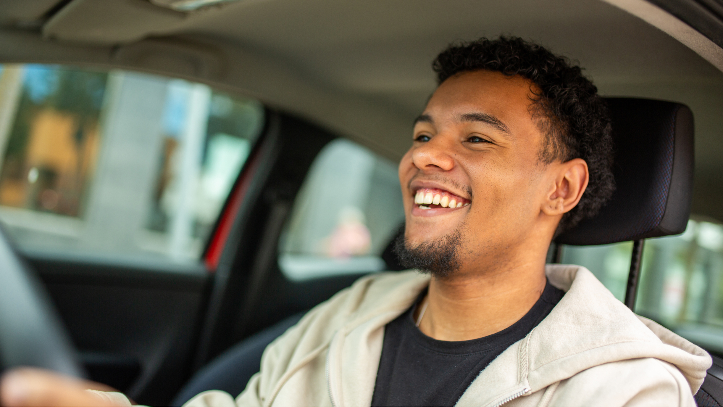 Lachender junger Mann im Auto