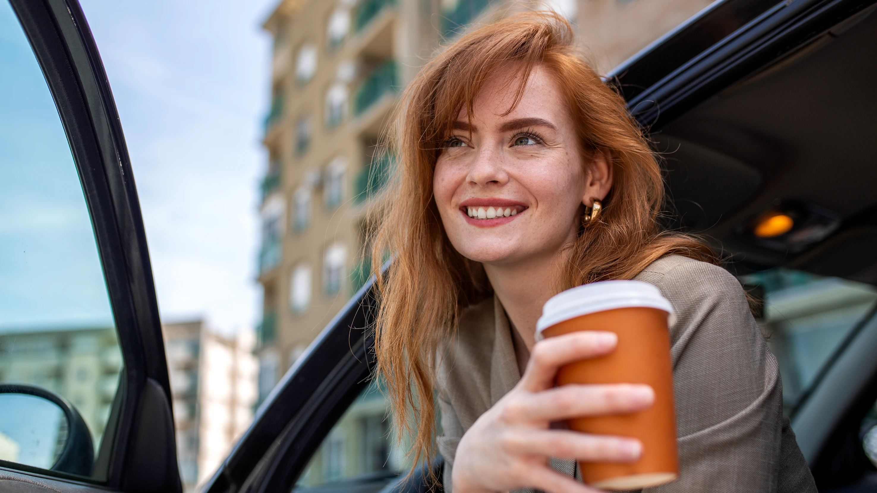 Lachende Frau mit Kaffeebecher in der Hand