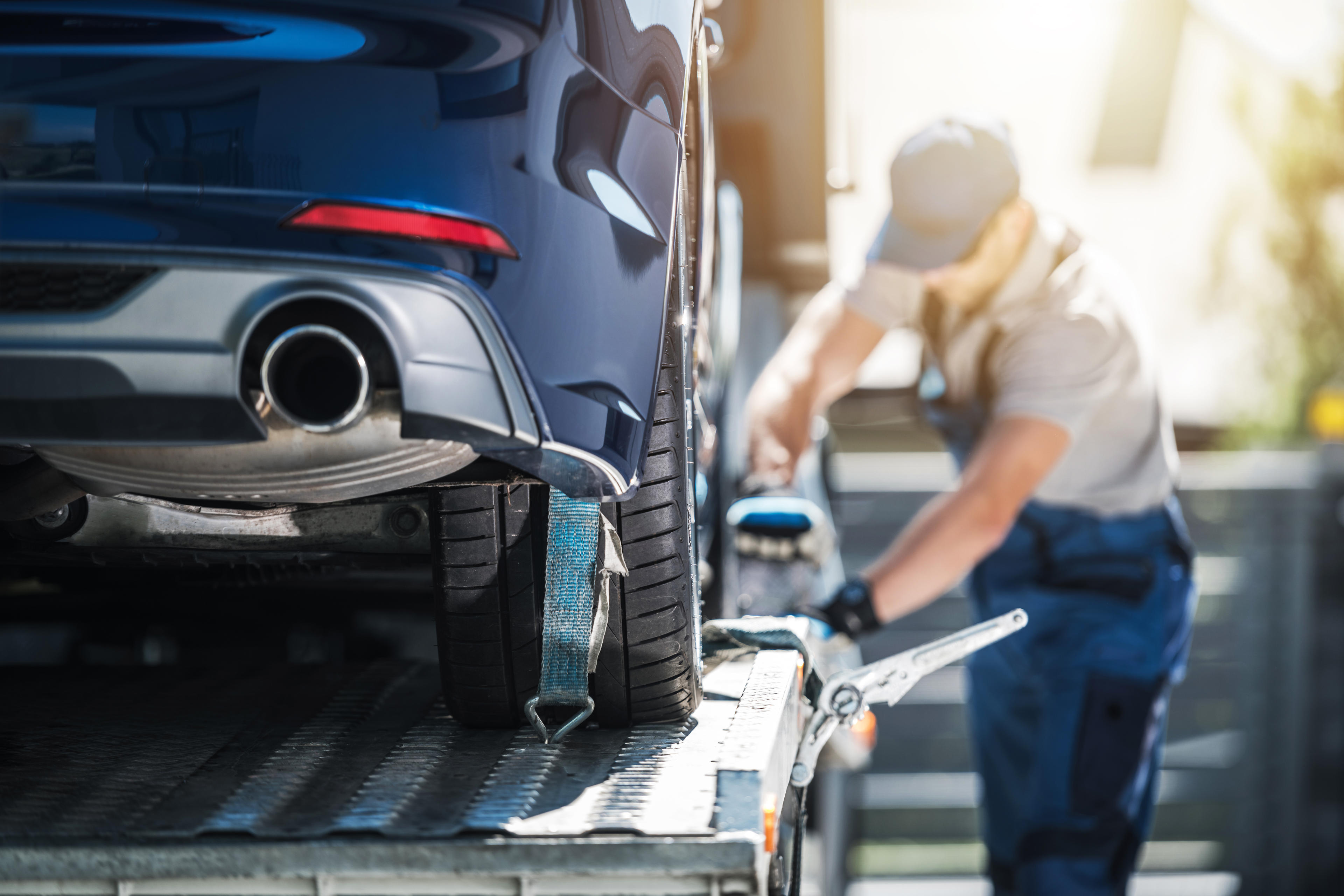 Ein Servicemitarbeiter befestigt ein Auto auf einem Anhänger