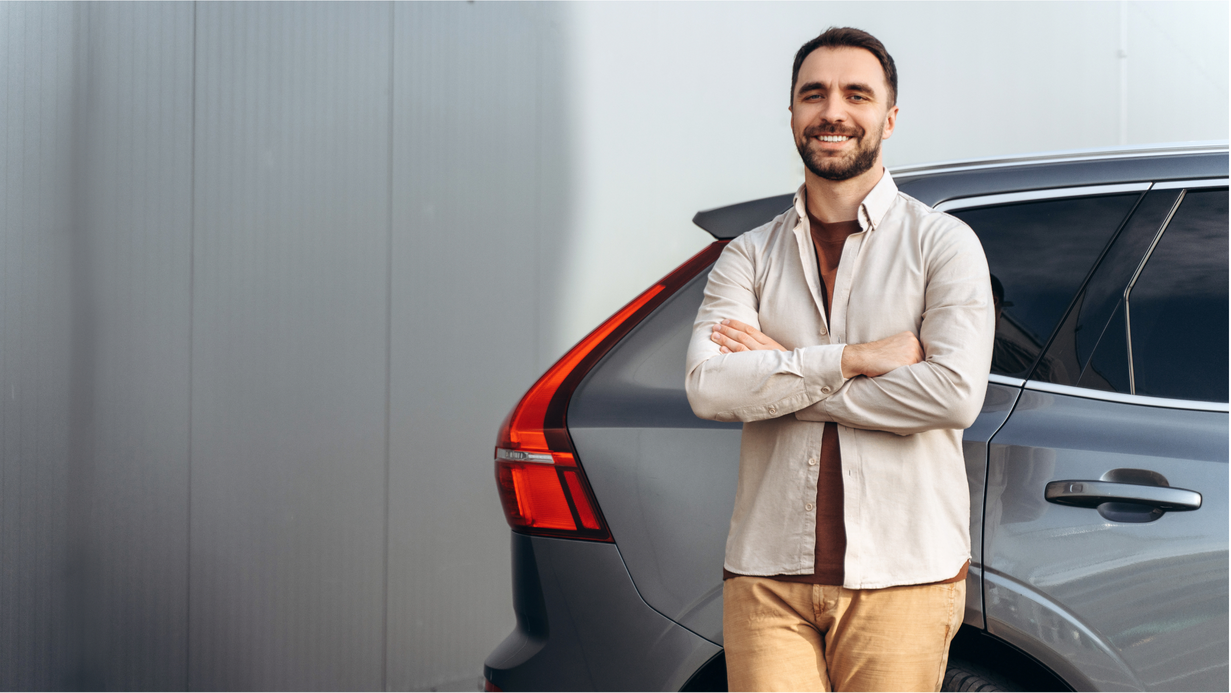 Mann lehnt entspannt an einem grauen SUV