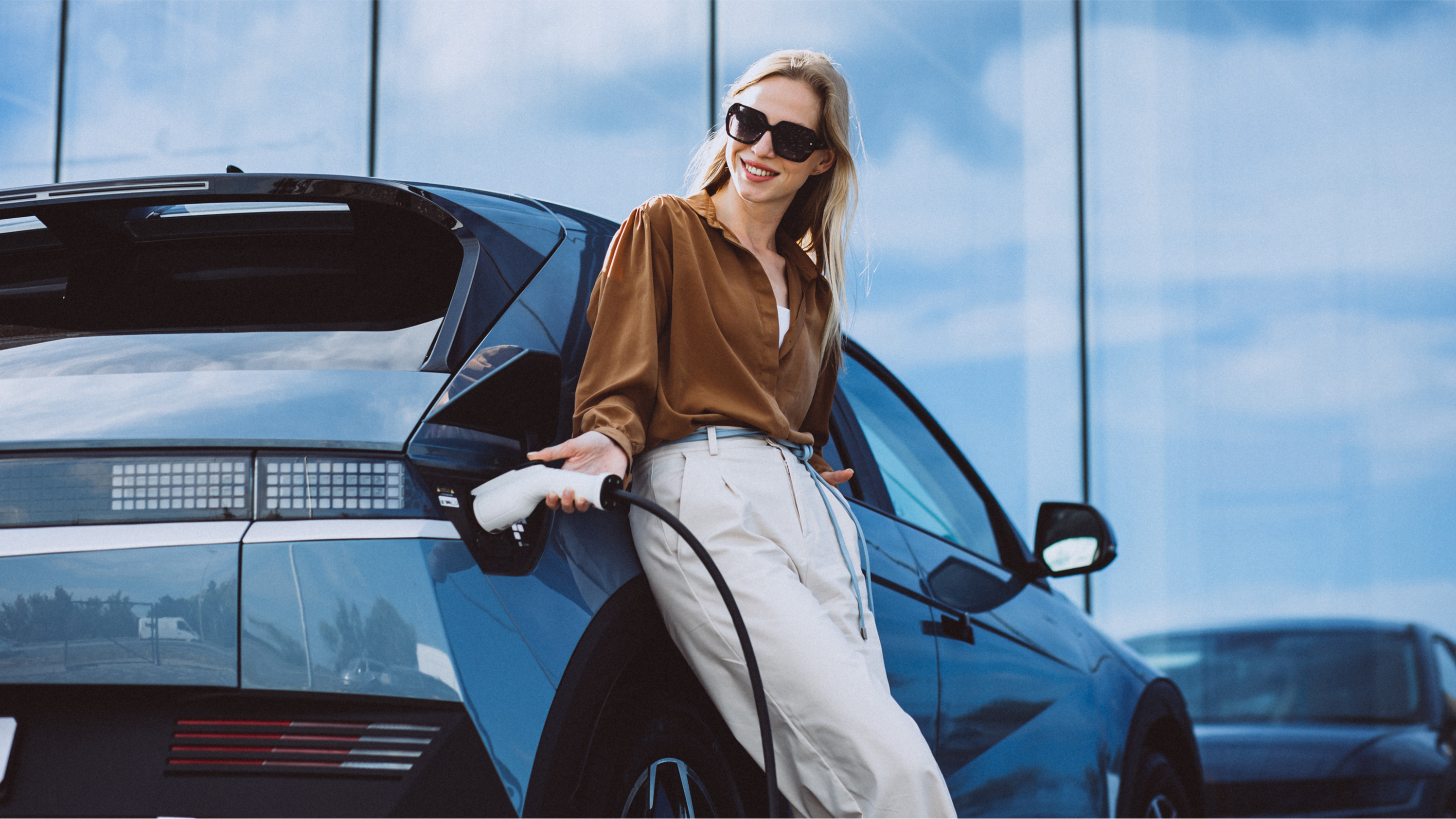 Frau lehnt an ihrem E-Auto