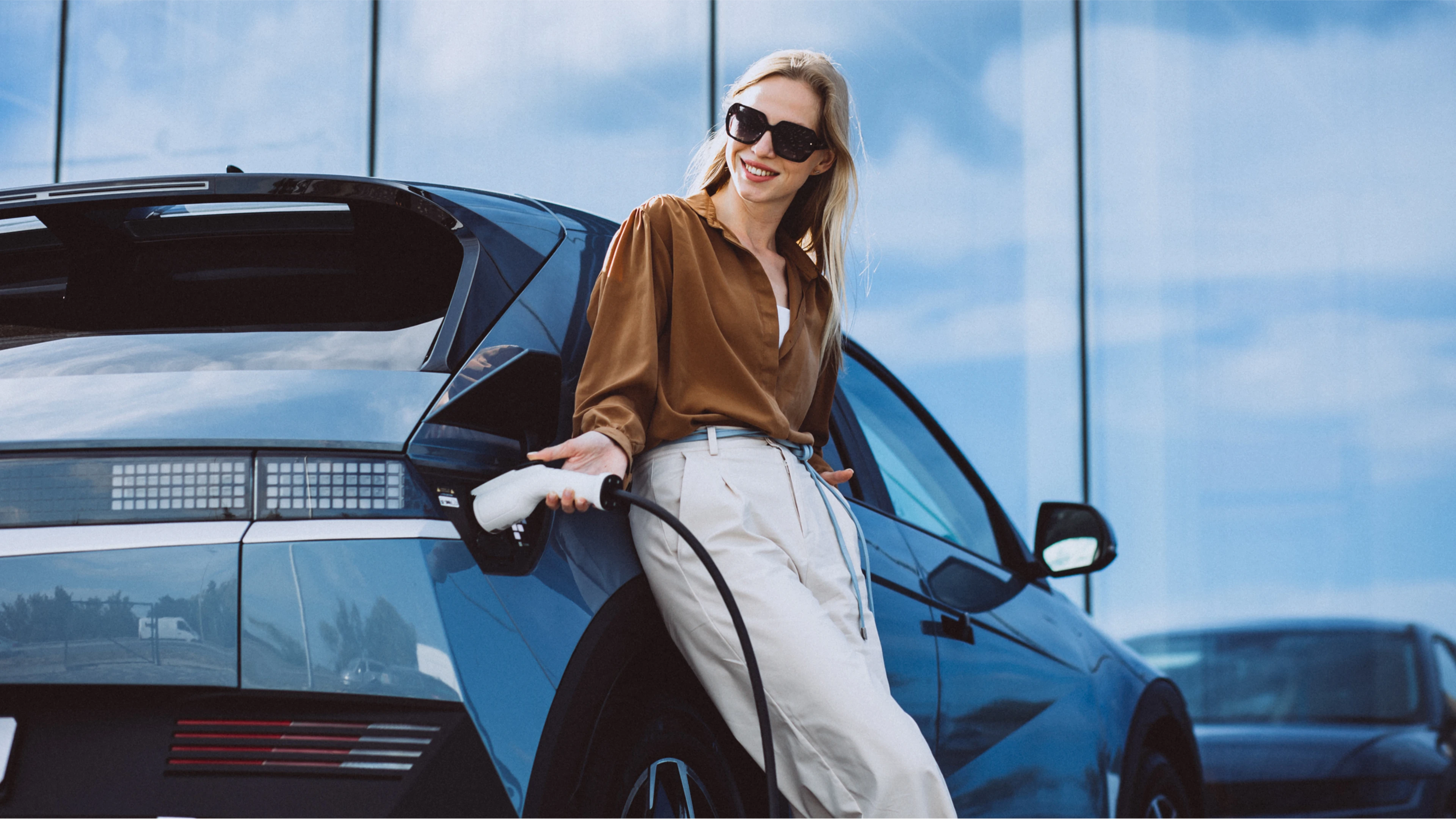 Frau lehnt an ihrem E-Auto