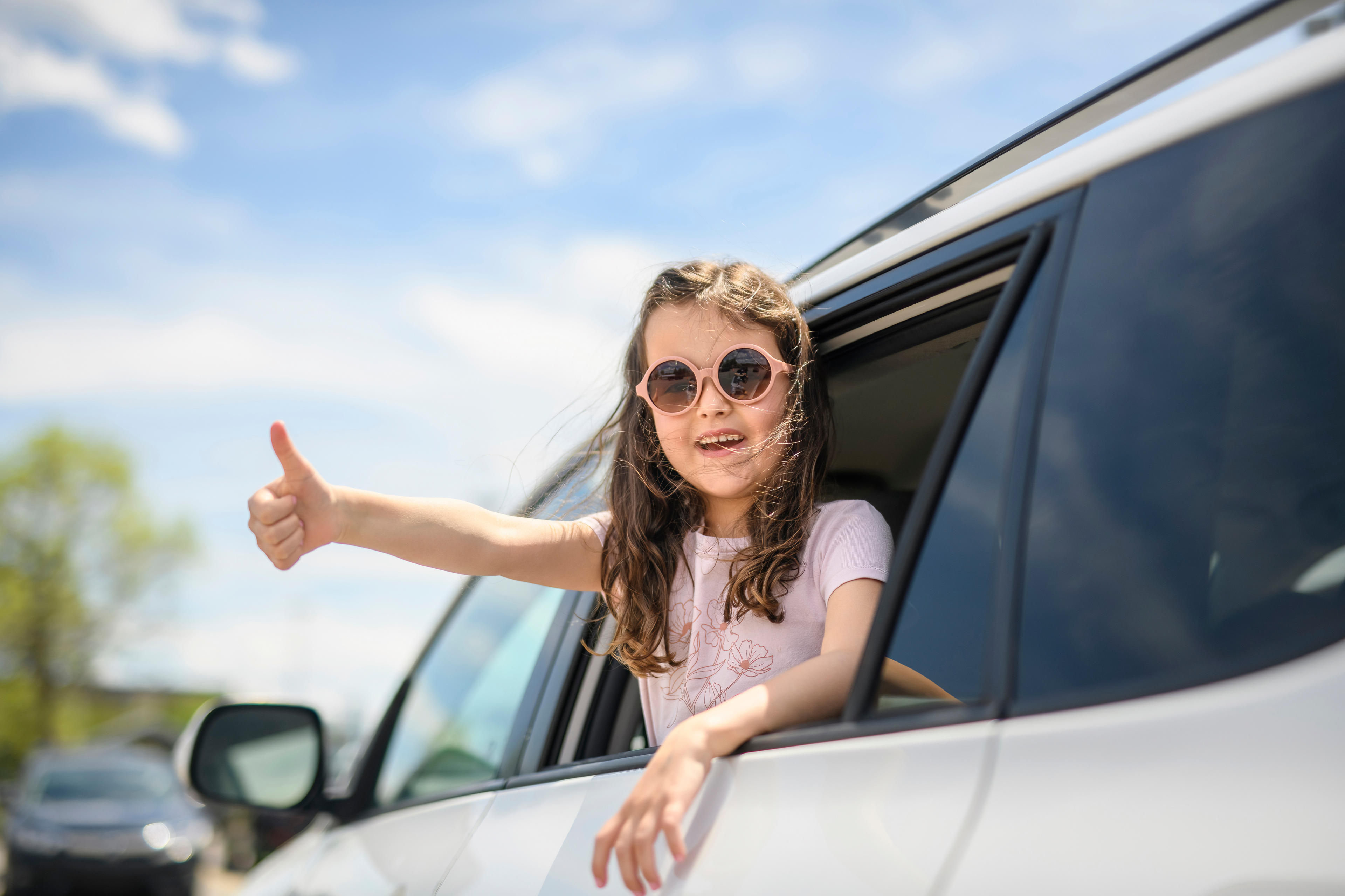 Kind hält Daumen aus dem Auto heraus hoch