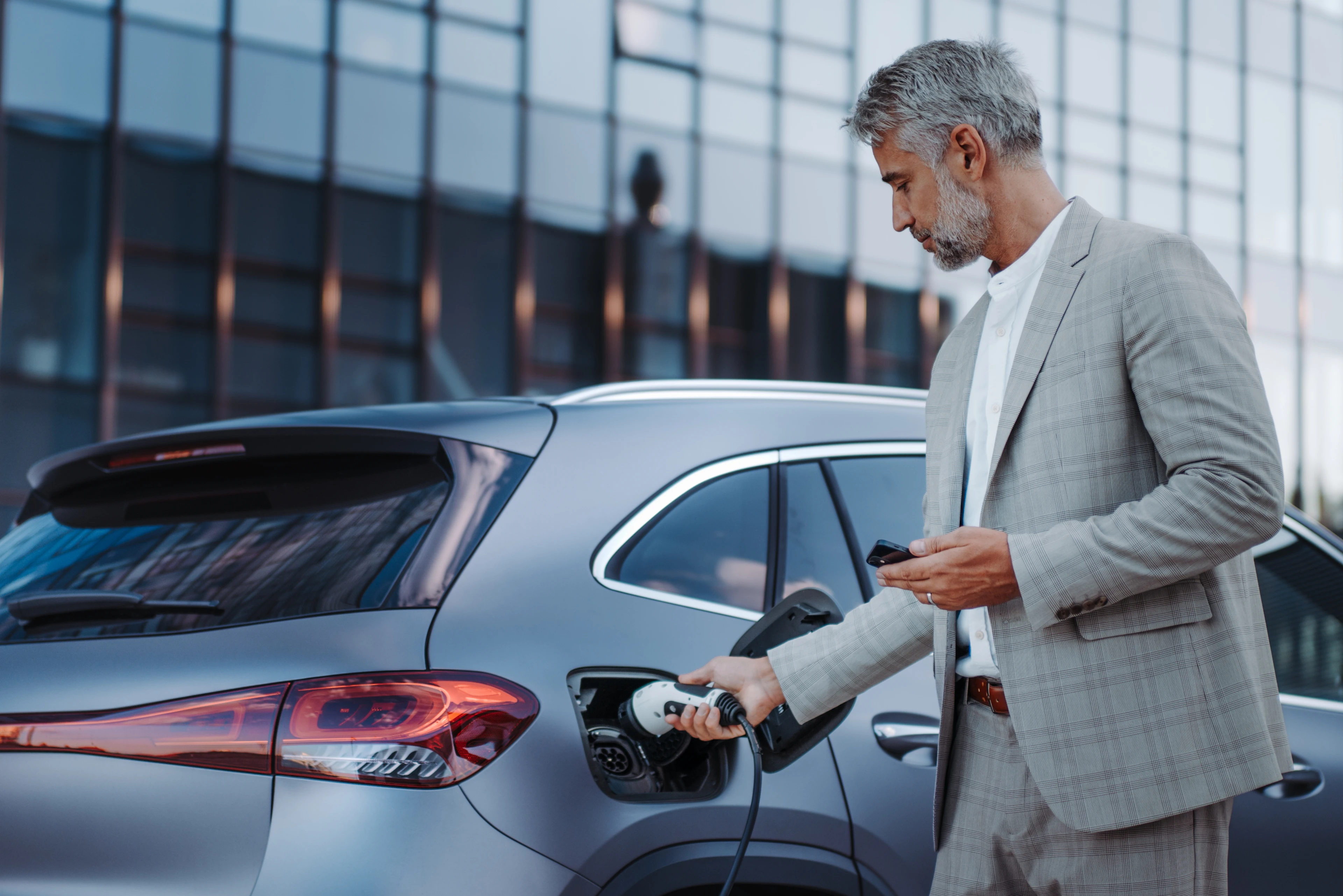 Mann lädt graues Elektroauto