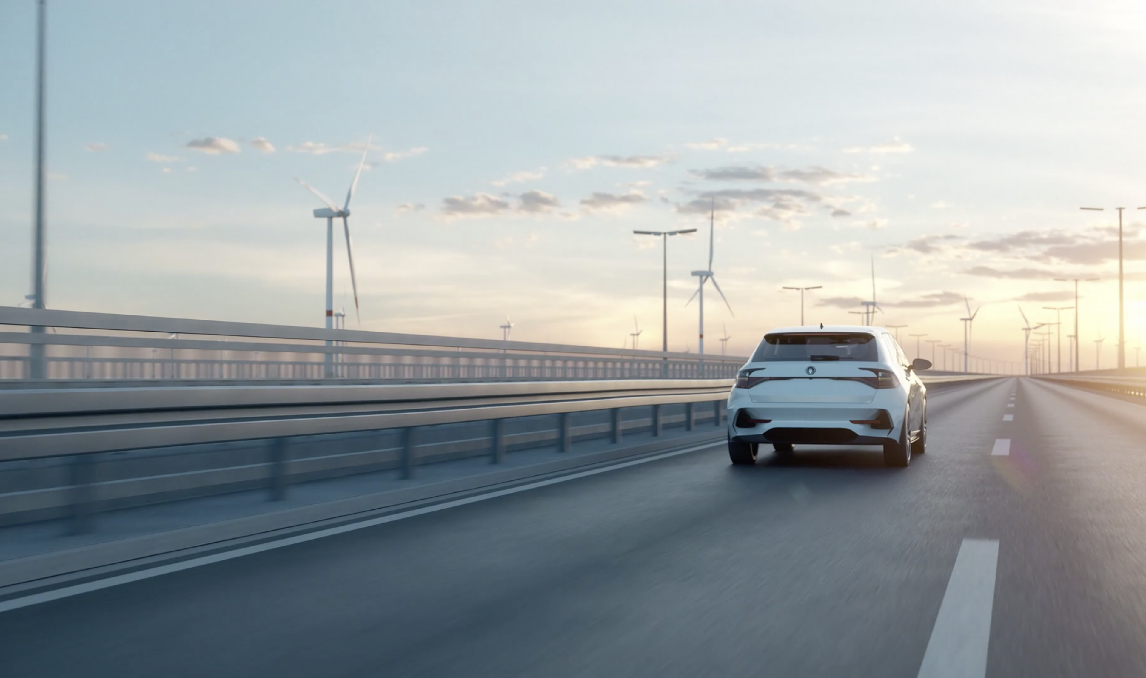 Auto fährt auf einer Brücke in den Sonnenaufgang. Im Hintergrund sieht man Windräder und den Himmel. 