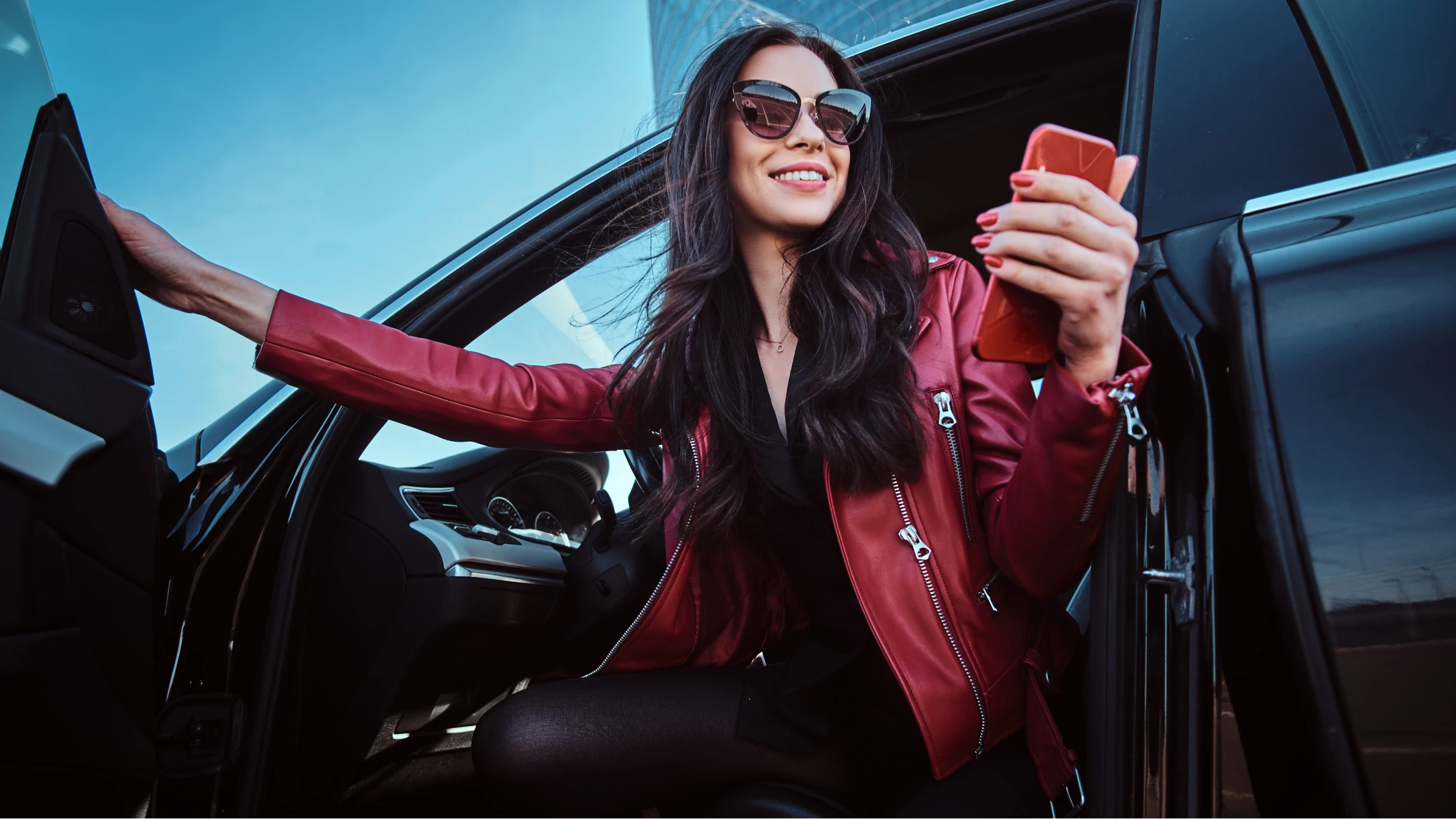 Frau mit roter Jacke steigt aus einem Auto