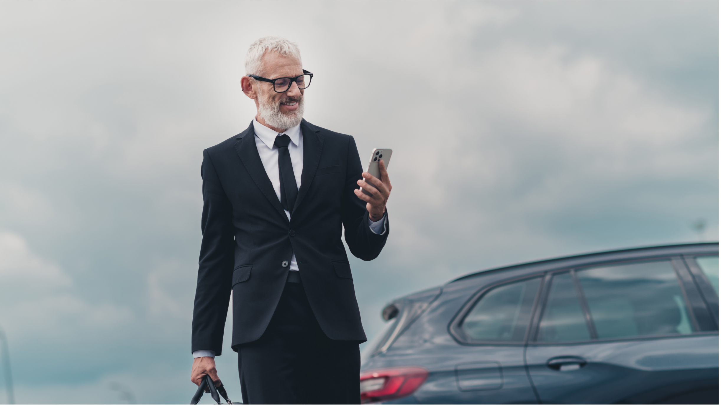 Mann mit Anzug und Smartphone blickt auf sein Smartphone
