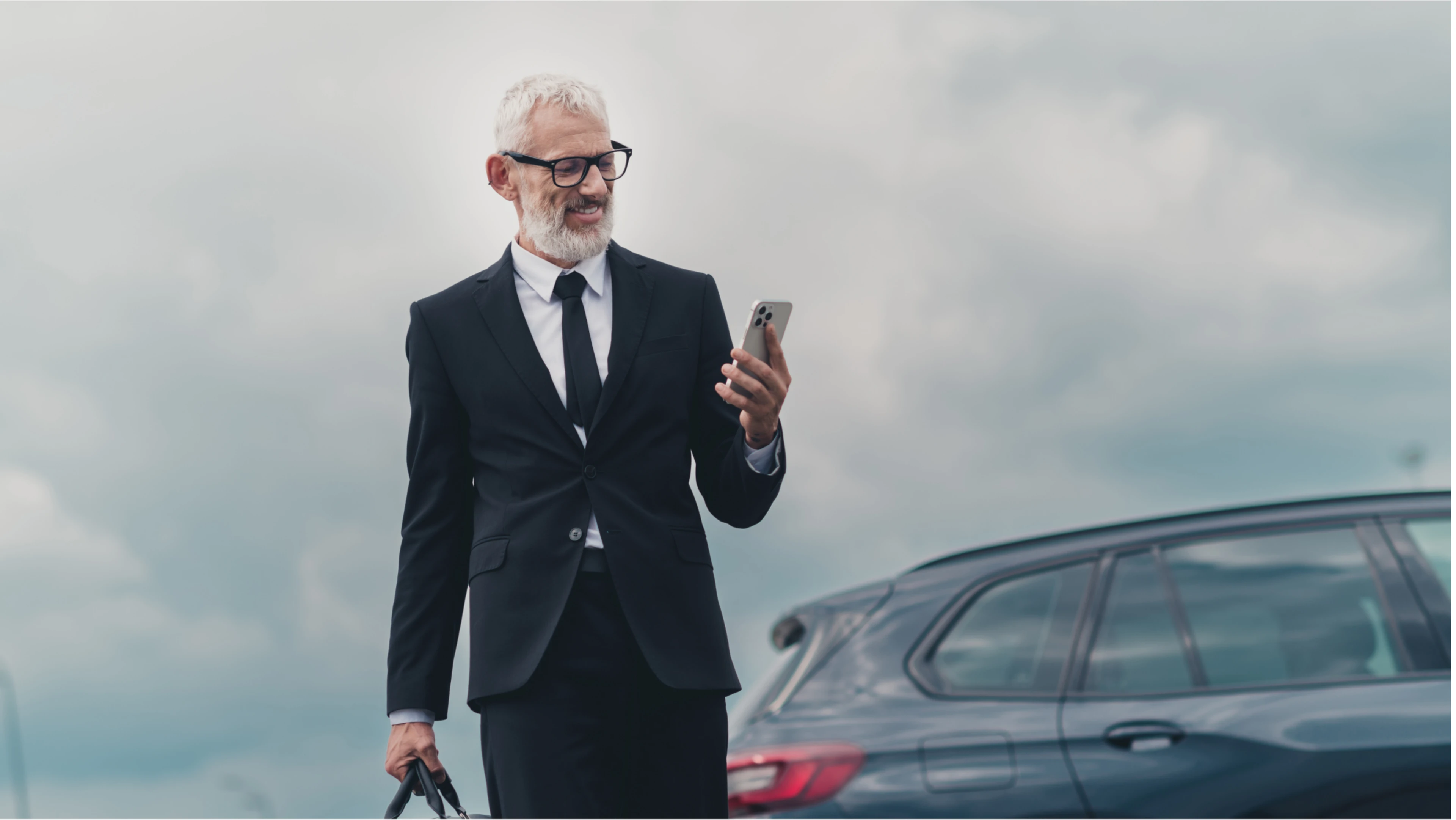 Mann mit Anzug und Smartphone blickt auf sein Smartphone