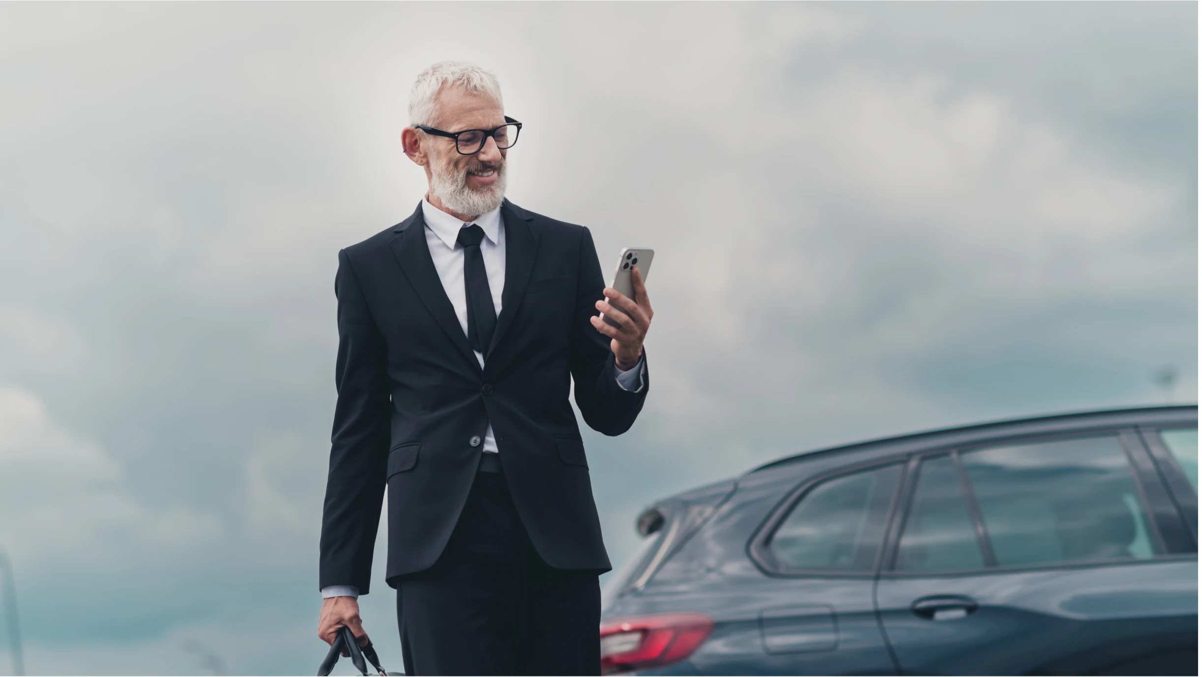 Mann mit Anzug und Smartphone blickt auf sein Smartphone
