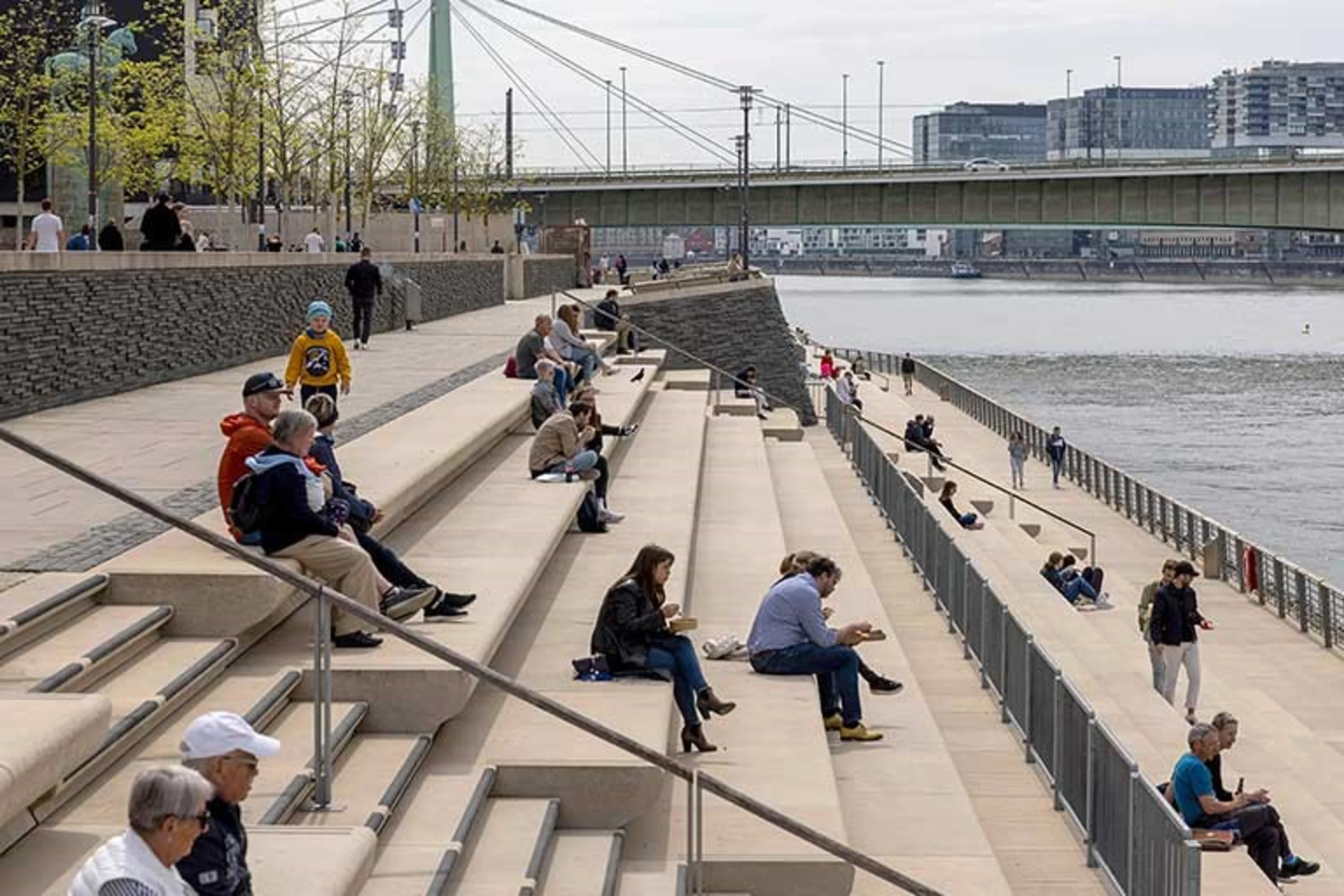 Foto: Die Rheintreppen in Köln mit Menschen, die auf den Rhein sehen