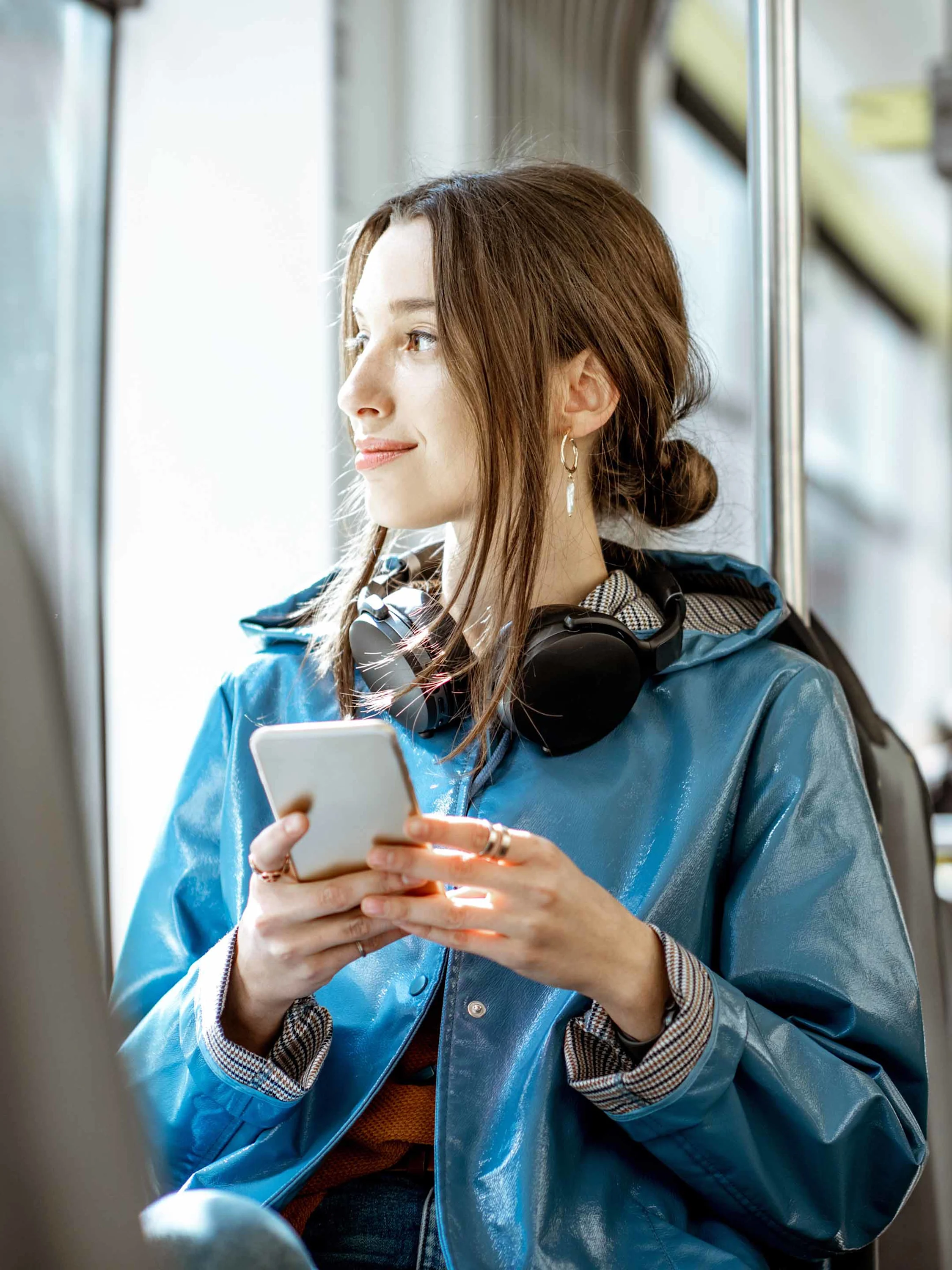 Foto: Junge Frau sitzt mit dem Smartphone im Bus