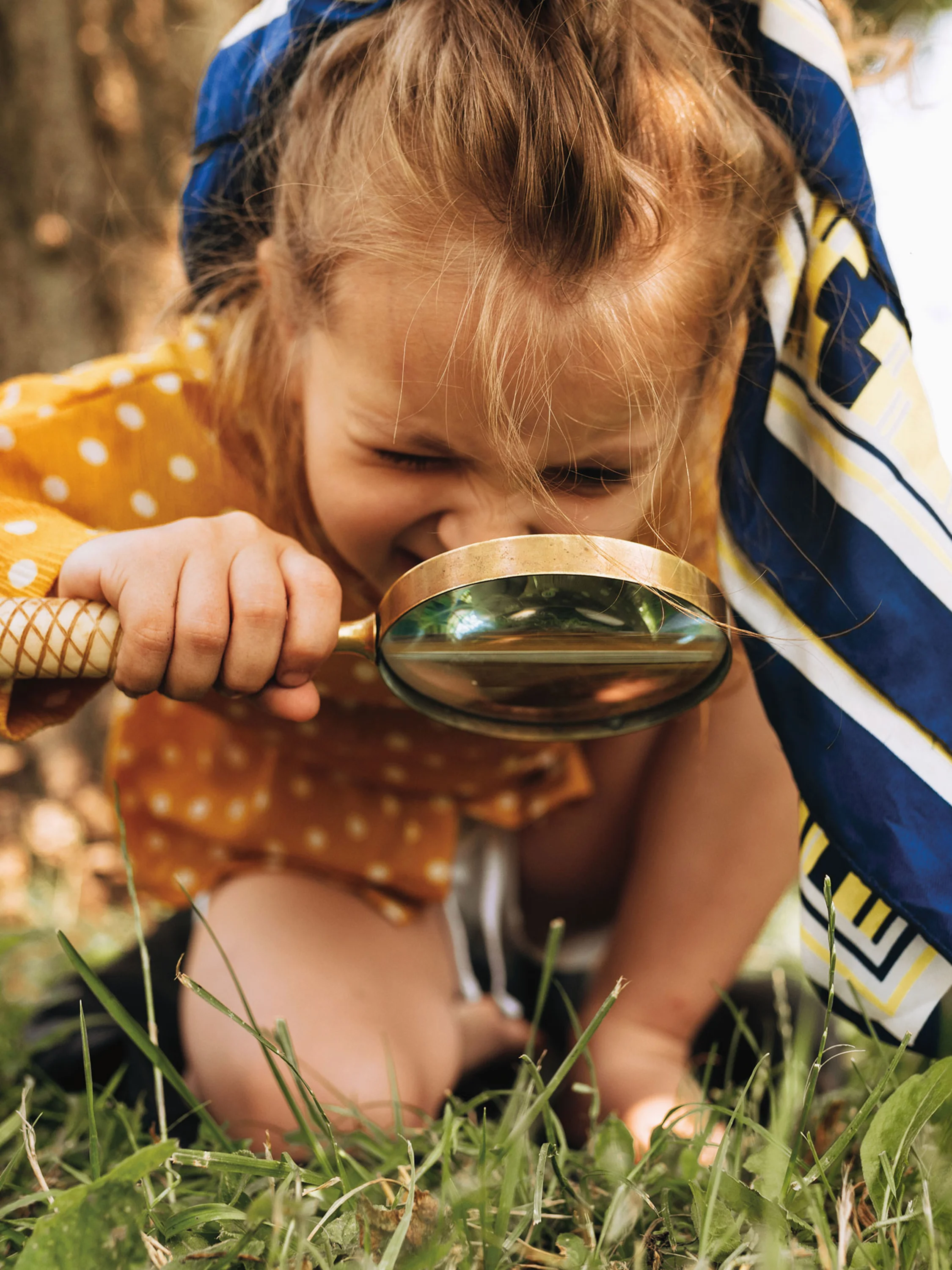 Photo: Child on the grass with a magnifying glass.