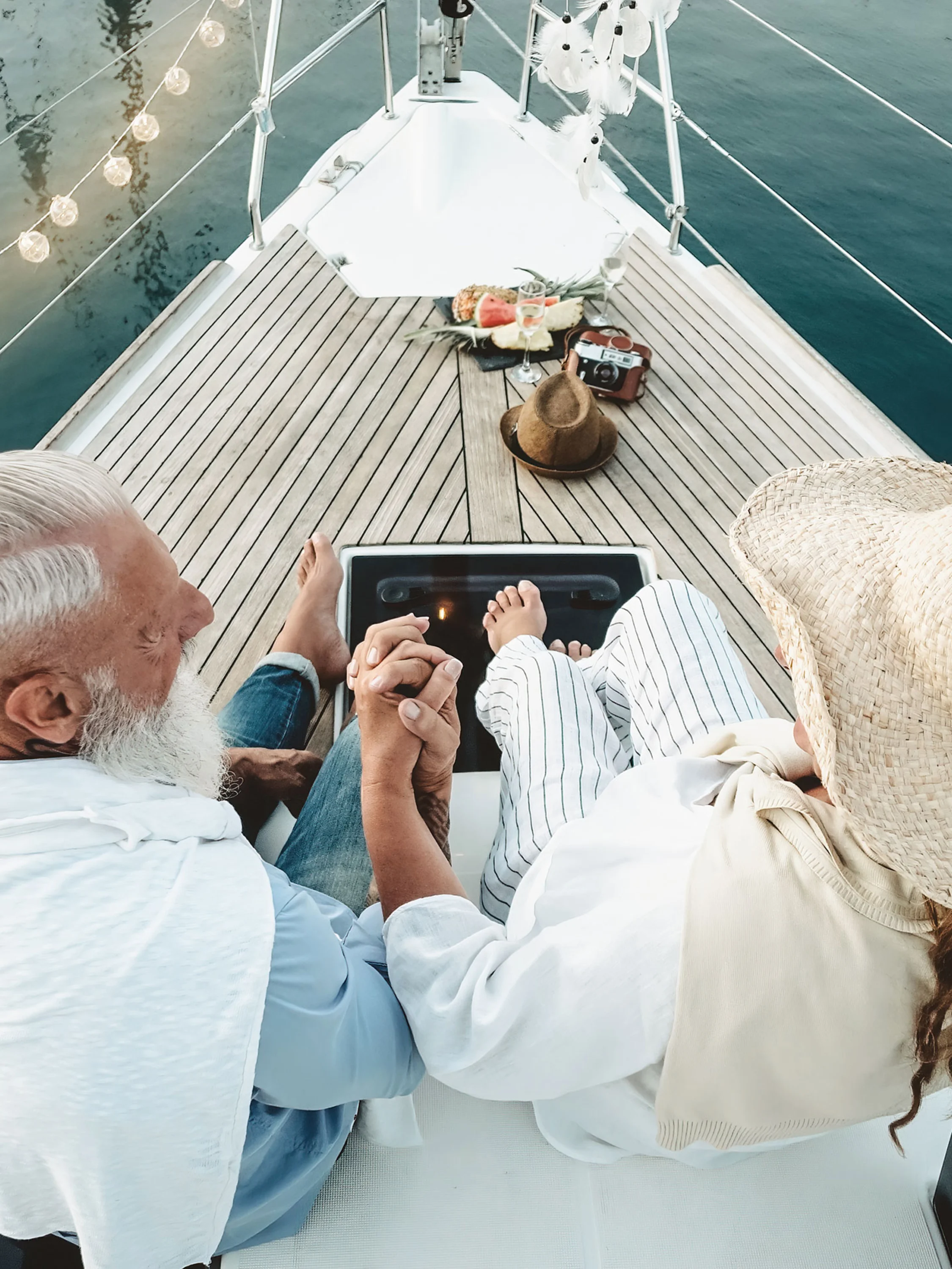 Pár sedí a drží sa za ruky na trupe lode a vychutnáva si večernú atmosféru.