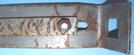 Metallisches Montageprofil mit rotbraunen Korrosionsspuren an Bohrungen, Kanten und Verbindungsstellen. Das Bild zeigt lokale Korrosion und Oberflächenverschlechterung eines Metallbauteils durch Umwelteinflüsse.