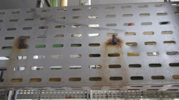 Perforierte Metallkabelrinne mit lokalen Rostspuren an Befestigungs- und Anschlussstellen. Das Bild zeigt Korrosion an Verbindungspunkten eines metallischen Tragsystems in einer technischen Installation.