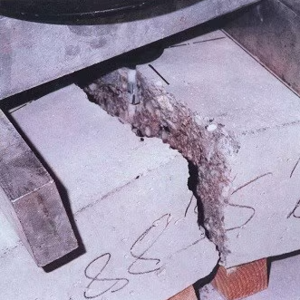 Un bloc de béton présentant une rupture par fendage sous l'effet de la charge transmise par un ancrage profondément implanté.