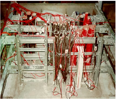 Fire test setup with cable trays densely packed with cables and numerous red wires draped and tangled across a metal frame, illustrating a complex cable installation scenario.