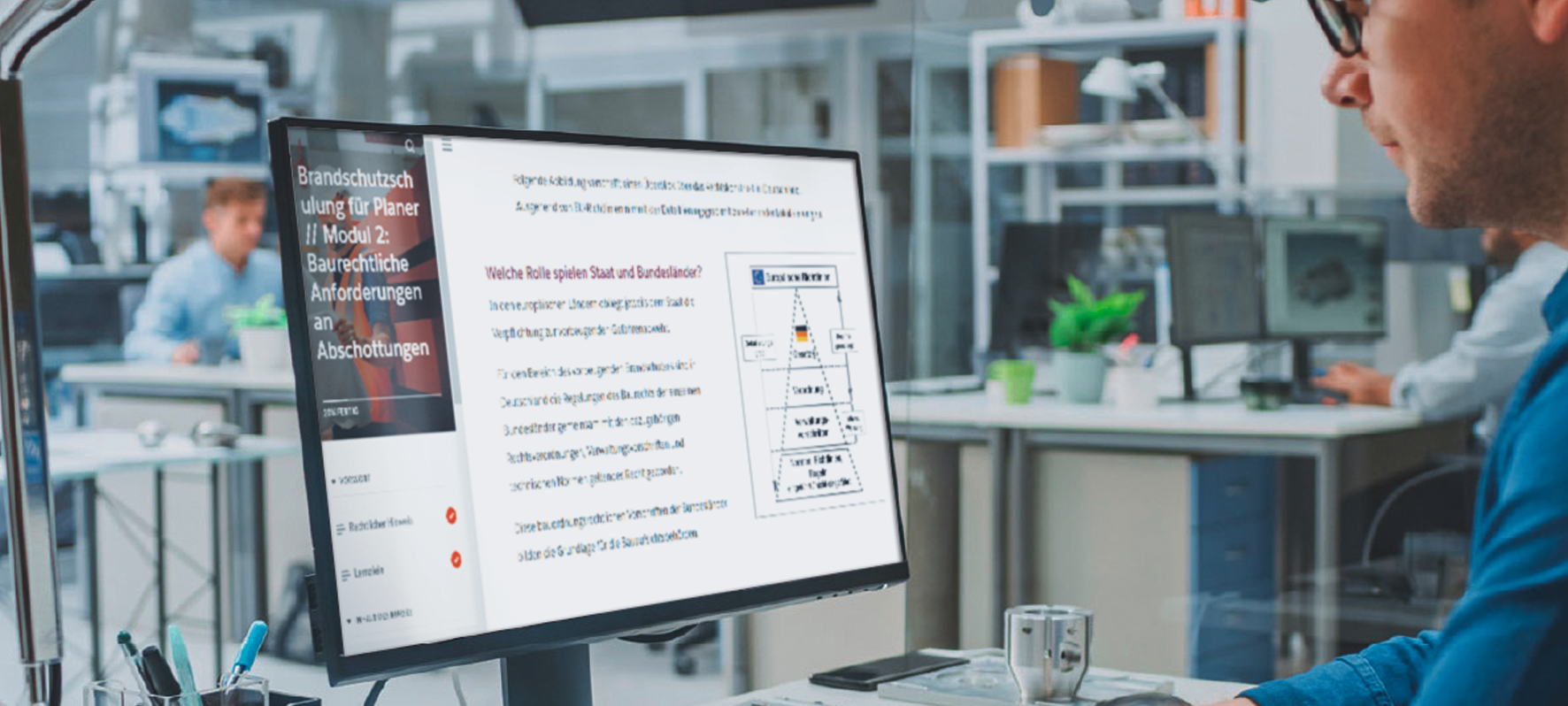 Eine Person betrachtet an einem Arbeitsplatz einen Online-Kurs zum Brandschutz auf einem Computerbildschirm. Die Anzeige enthält Schulungsinhalte, Navigationsmenüs sowie technische Informationen zu Brandschutz und Bauvorschriften.
