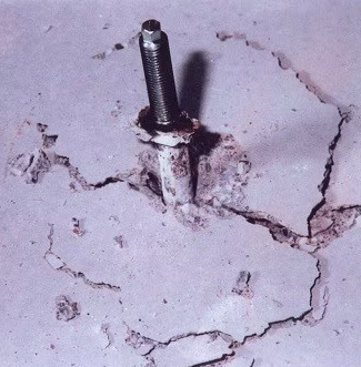 Cheville post-installée entourée d'un cône de béton fissuré, illustrant une rupture du cône de béton sous effort de traction