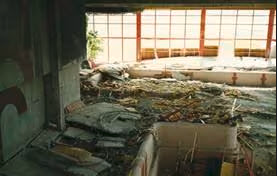 Innenraum eines stark beschädigten Gebäudes mit verstreuten Trümmern und sichtbaren Bauschäden. Das Bild steht im Zusammenhang mit dem Unglück von Uster 1985 und veranschaulicht die Folgen schwerwiegender Gebäudeschäden.