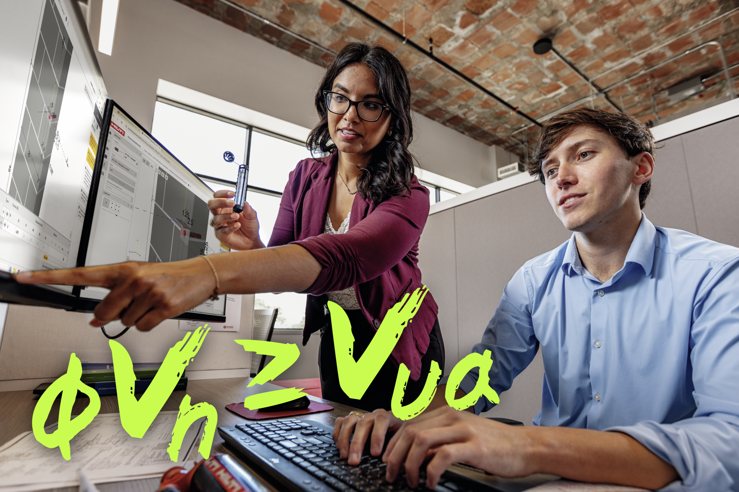 Image of 2 people working at a desk looking at computer monitor with PROFIS software on it