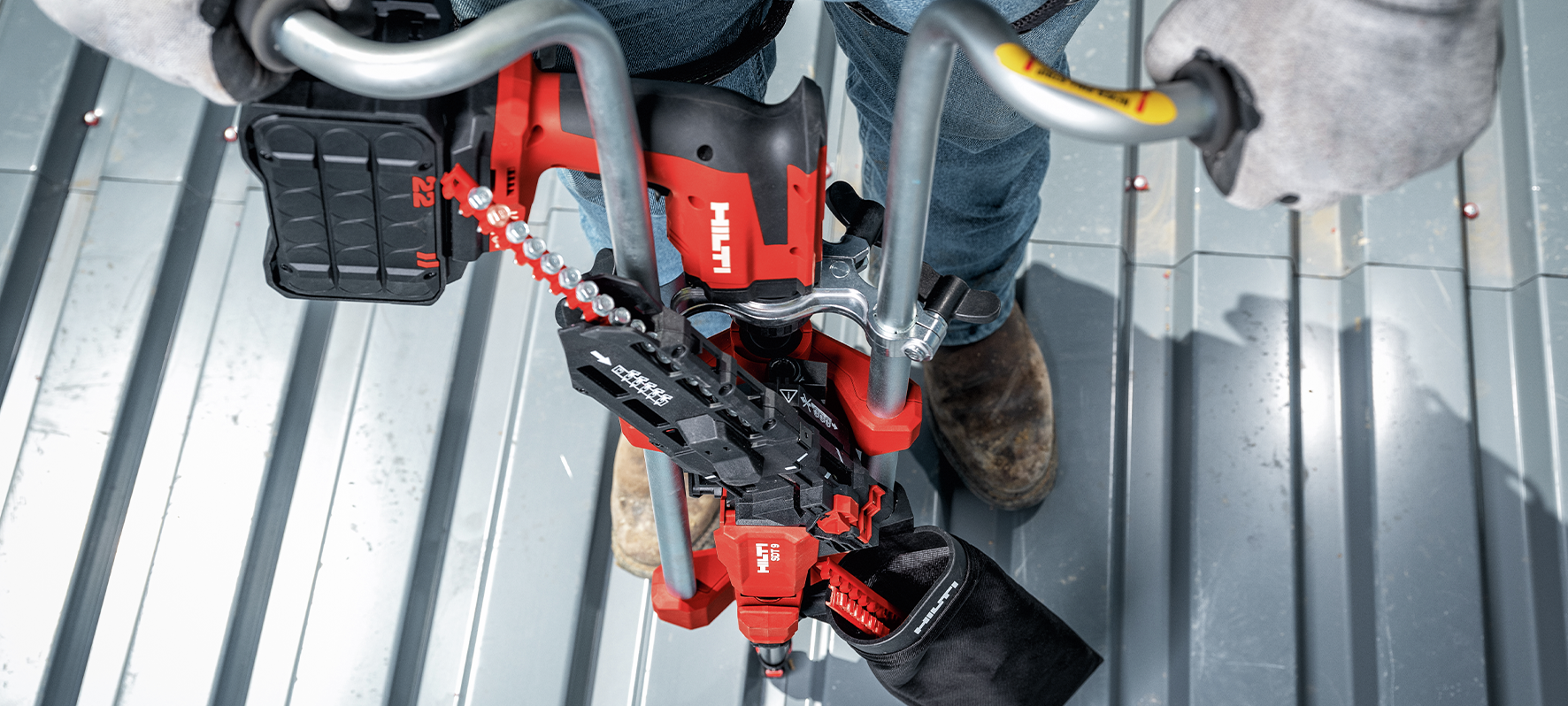 Application image of a worker installing screws on a metal roof deck, using the Nuron ST 2000-22 and SDT 9