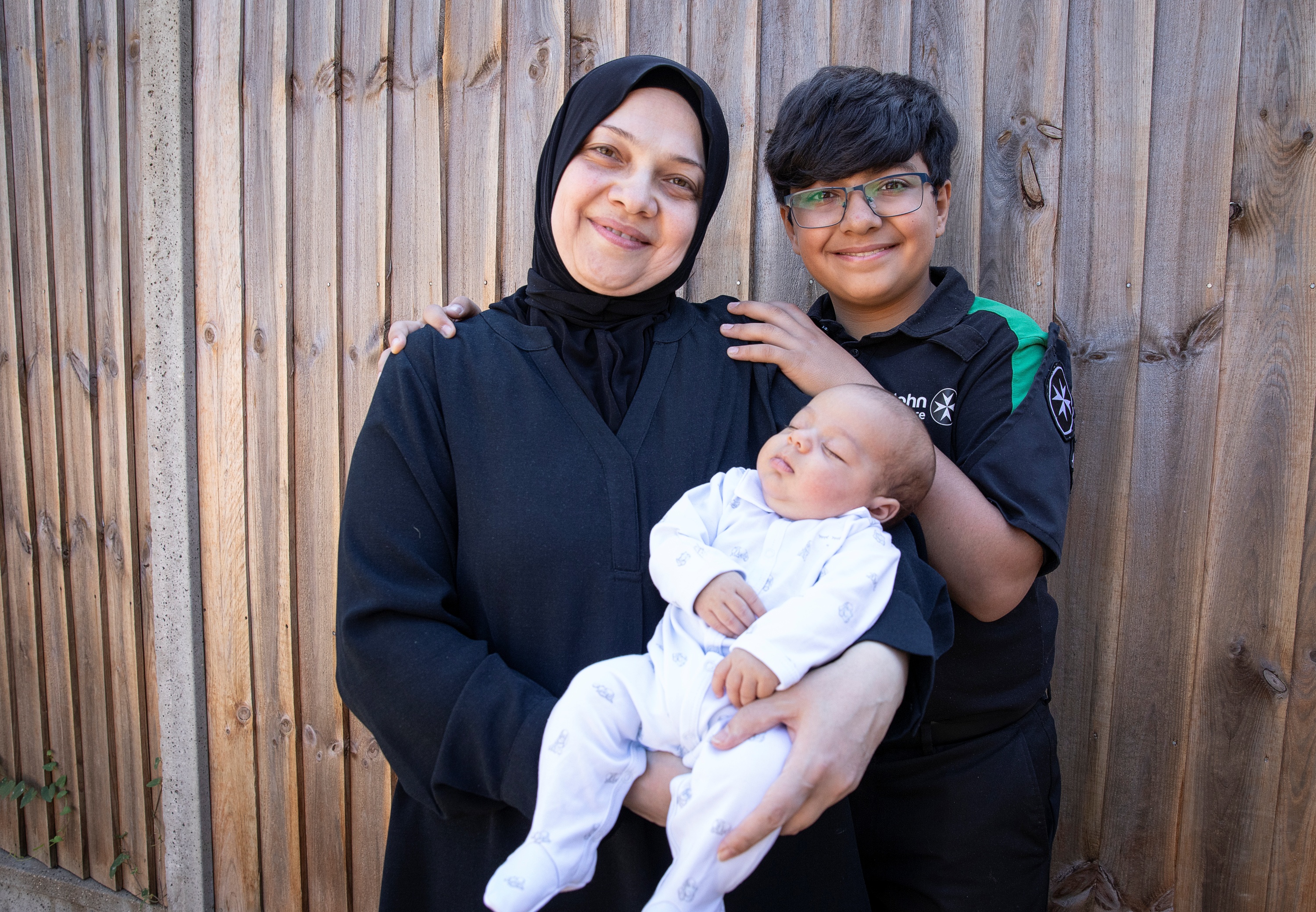 St John Ambulance Cadet, Maitham, standing next to his mum who is holding his baby brother, Mohammad-Jawad.