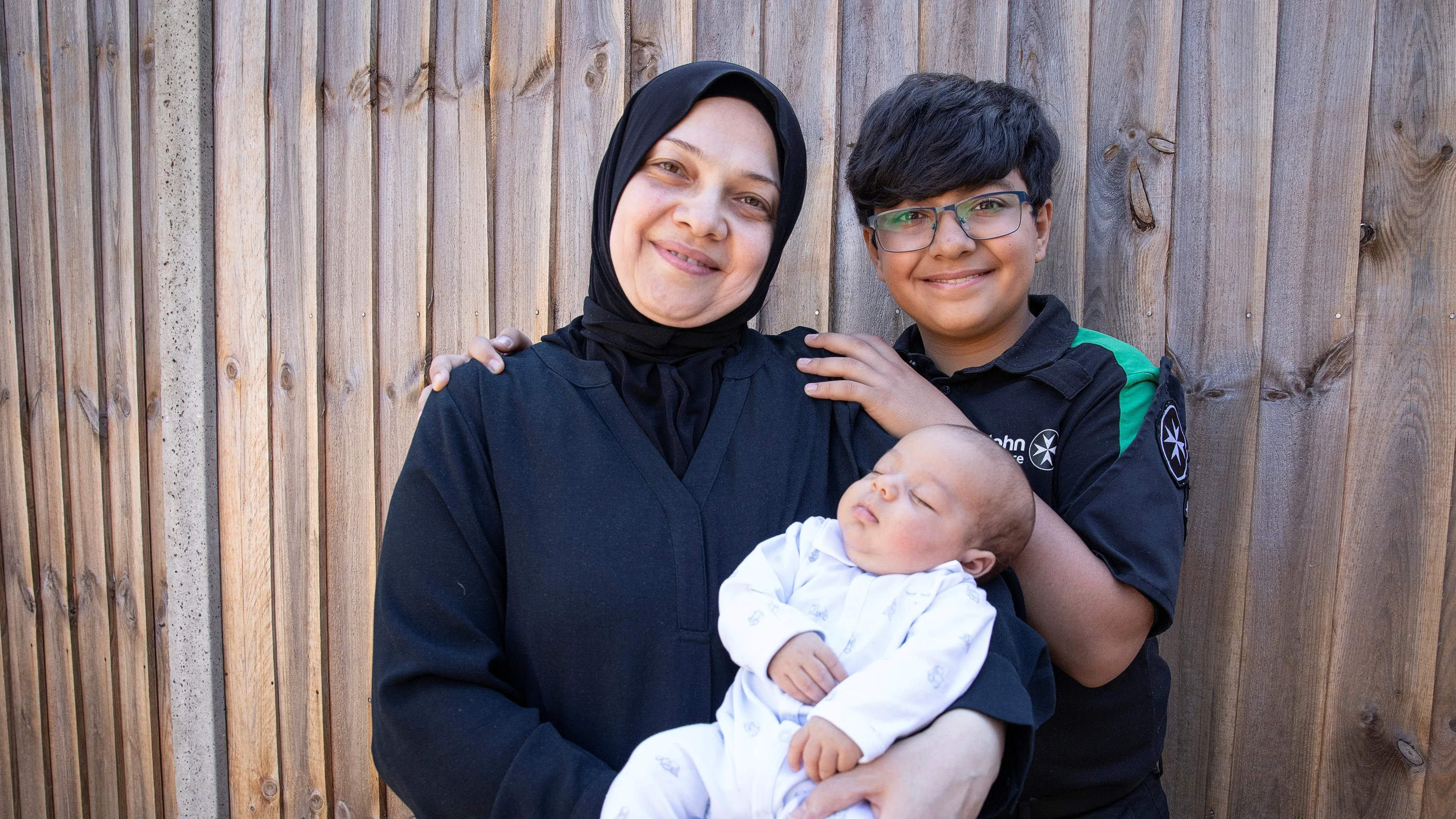 St John Ambulance Cadet, Maitham, standing next to his mum who is holding his baby brother, Mohammad-Jawad.