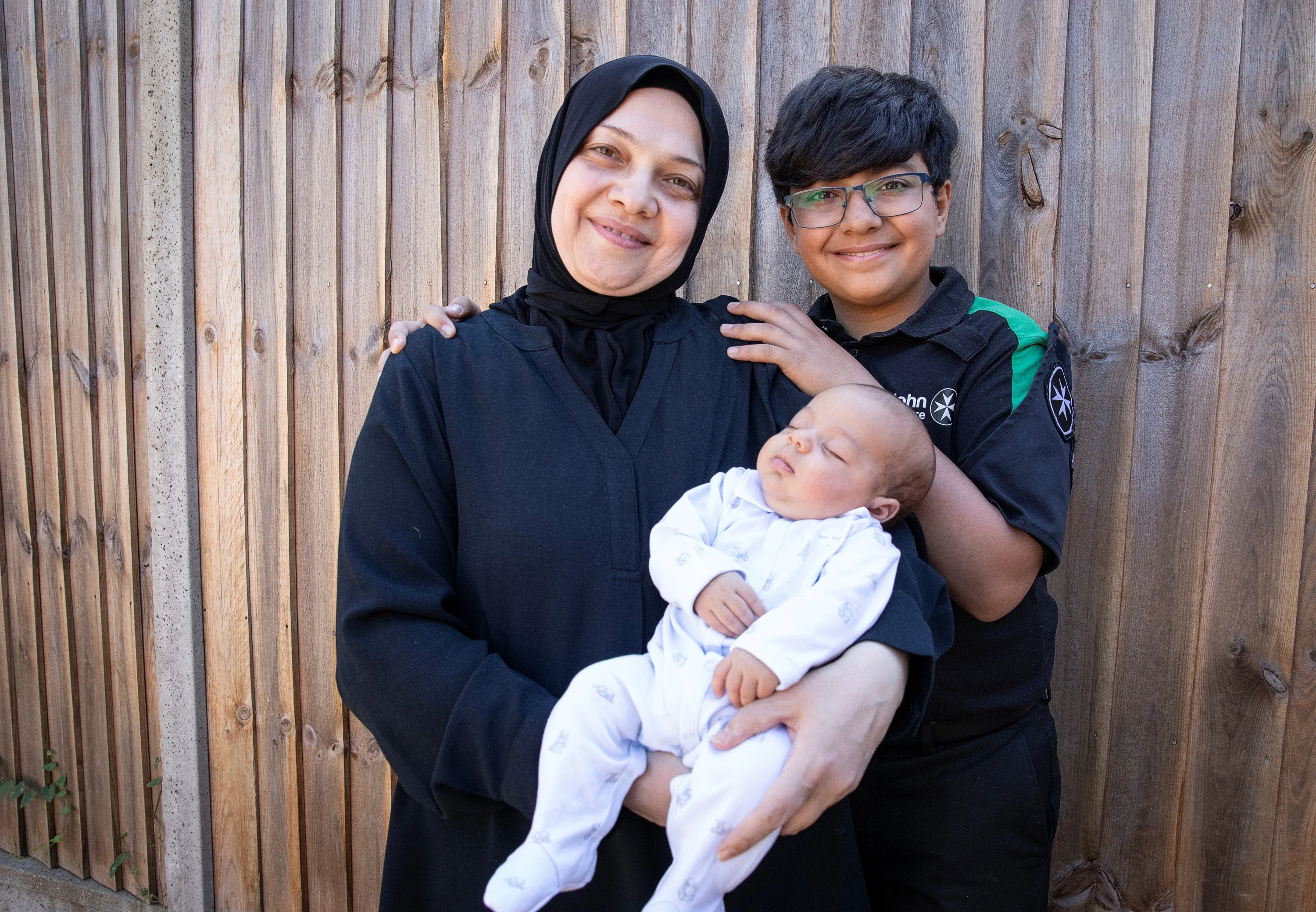 St John Ambulance Cadet, Maitham, standing next to his mum who is holding his baby brother, Mohammad-Jawad.