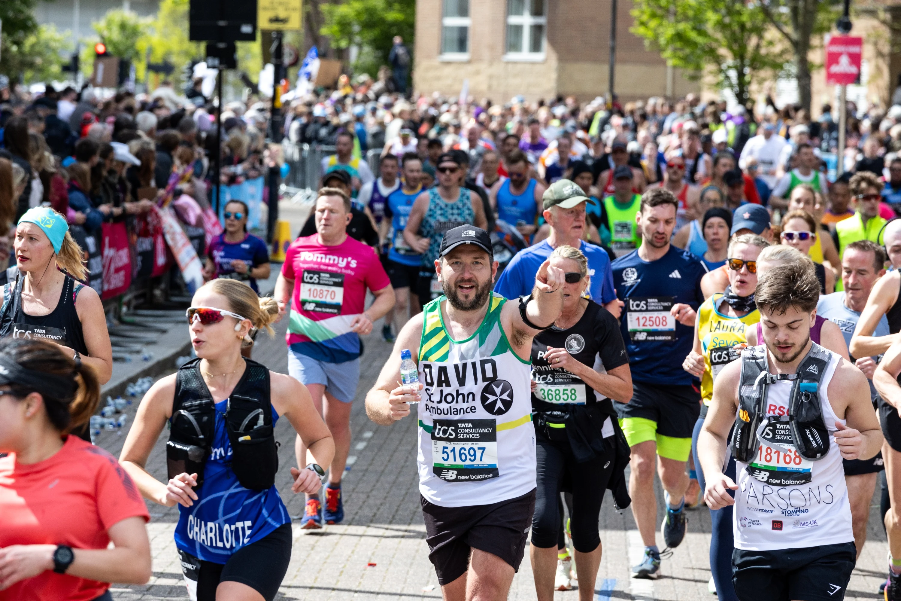 A crowd of marathon runners, with someone running for St John Ambulance at the centre.