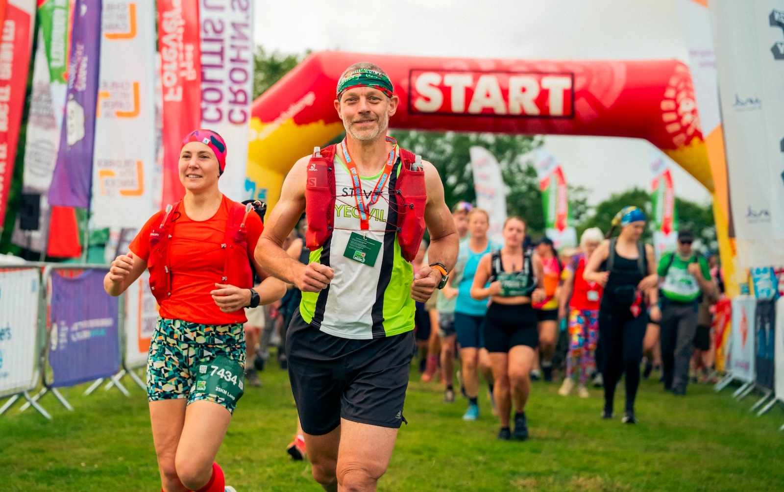 A group of people taking part in Kent Downs 50 Ultra Challenge, running from below a banner with 'Start' on it.
